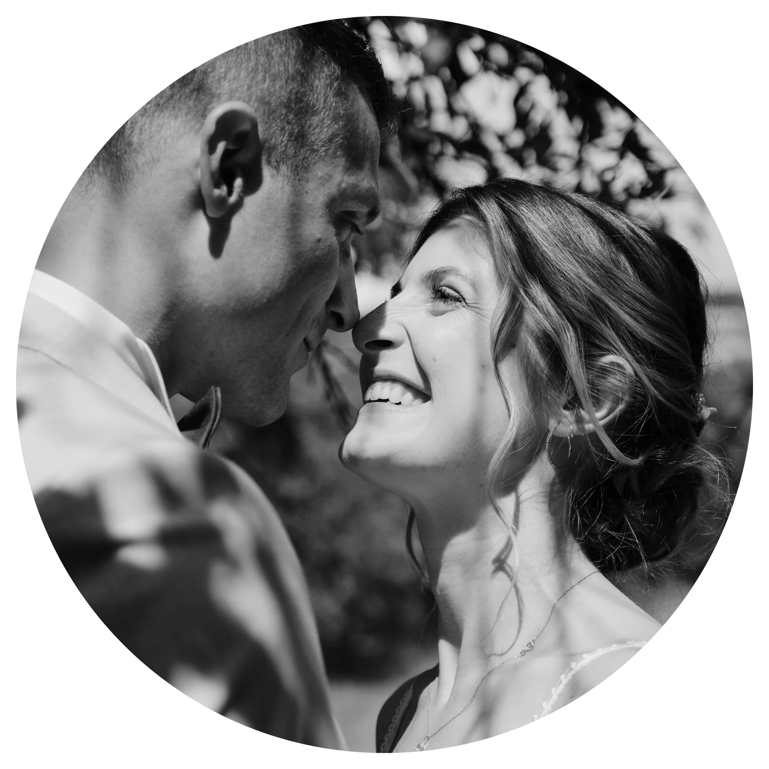 Un couple souriant face à face en noir et blanc, probablement le jour de leur mariage.