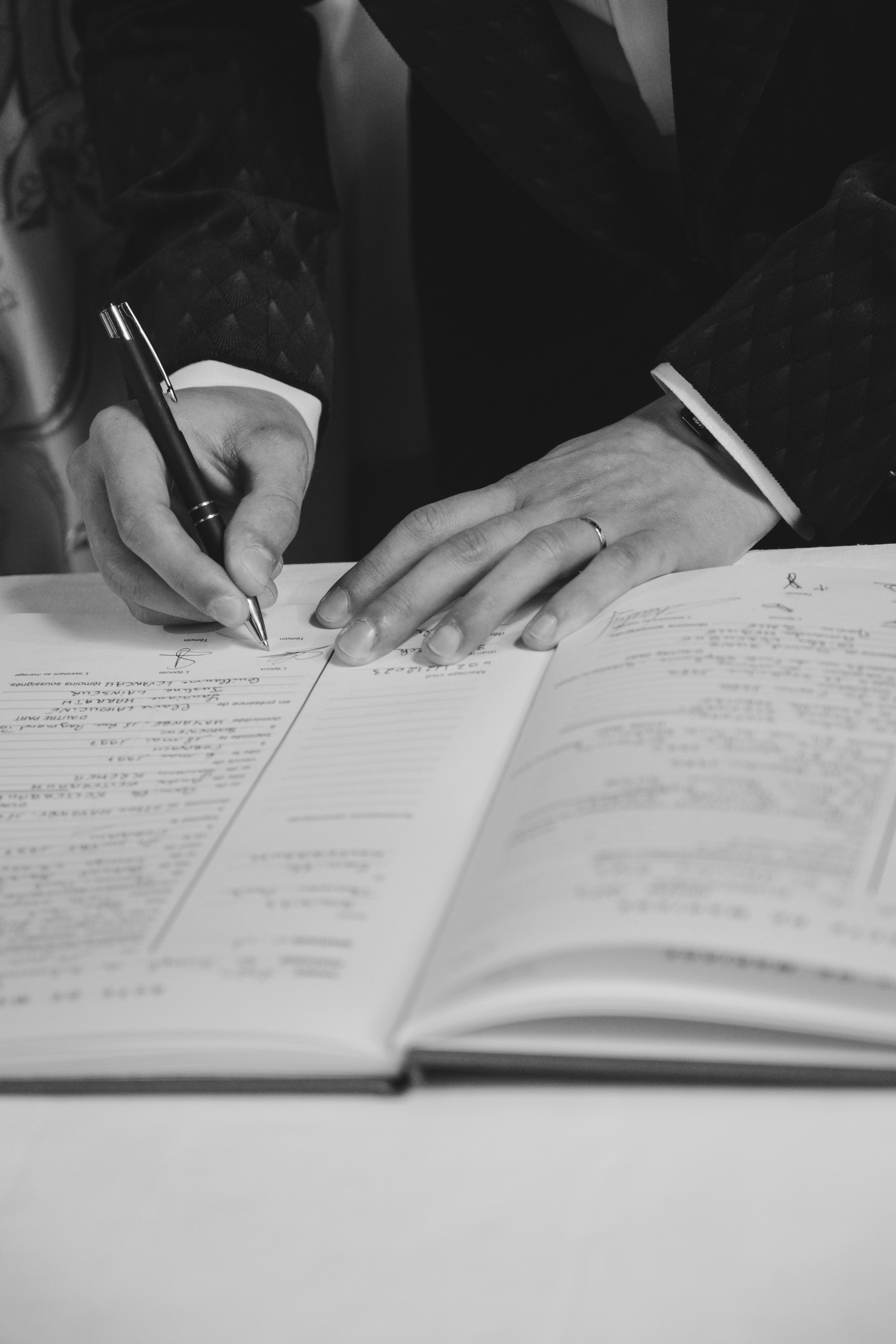 Personne signant un document officiel avec un stylo, gros plan sur les mains et le document.