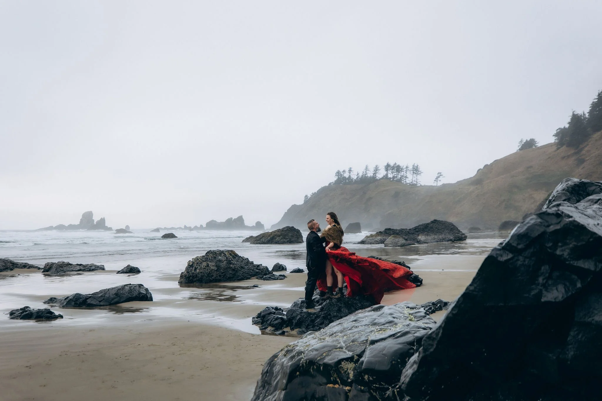 Couple eloping at Crescent Beach in Ecola State Park on the Oregon Coast, standing on a rocky shoreline during a moody coastal elopement