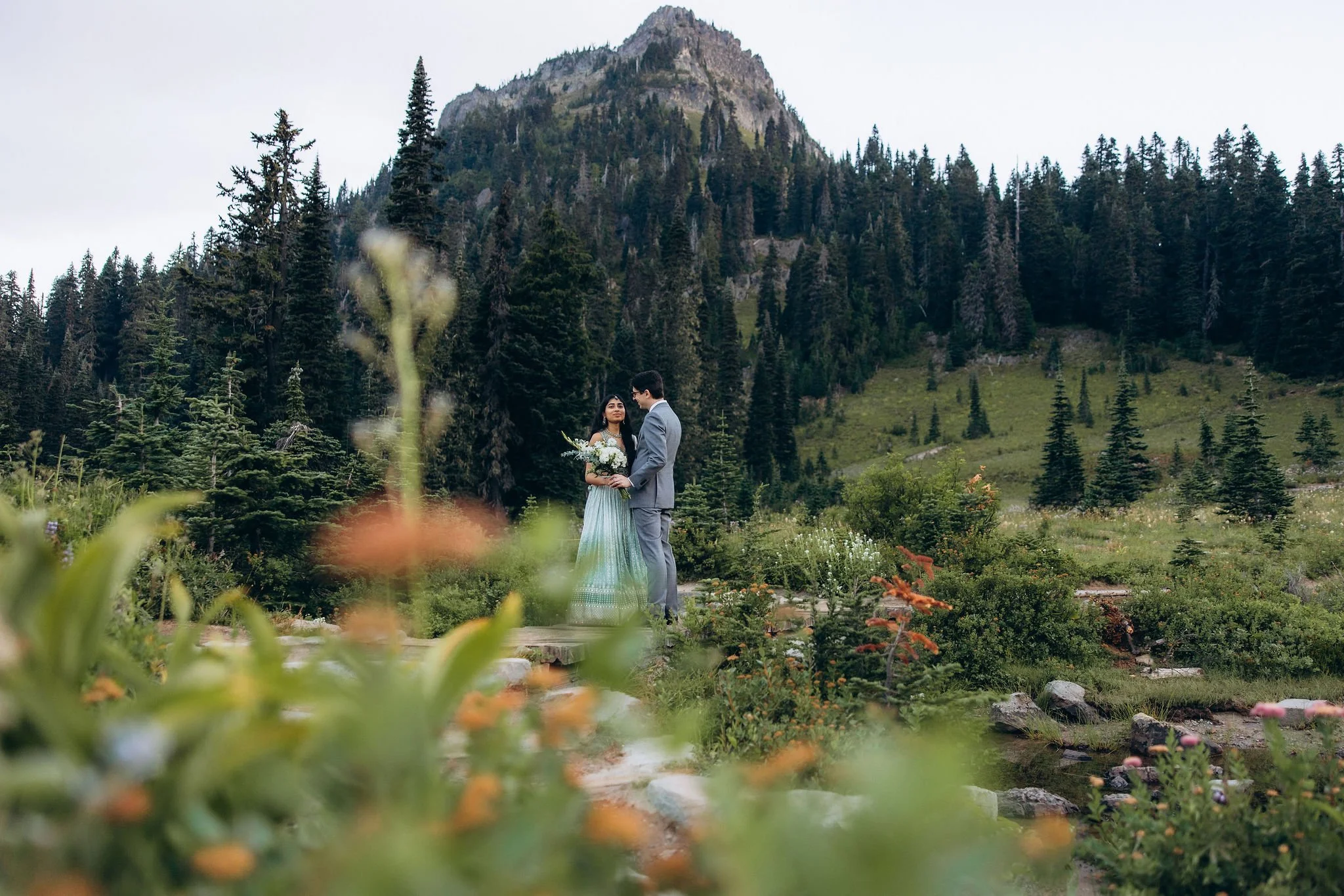 Couple eloping at sunrise at Tipsoo Lake in Mount Rainier National Park surrounded by wildflowers and alpine peaks