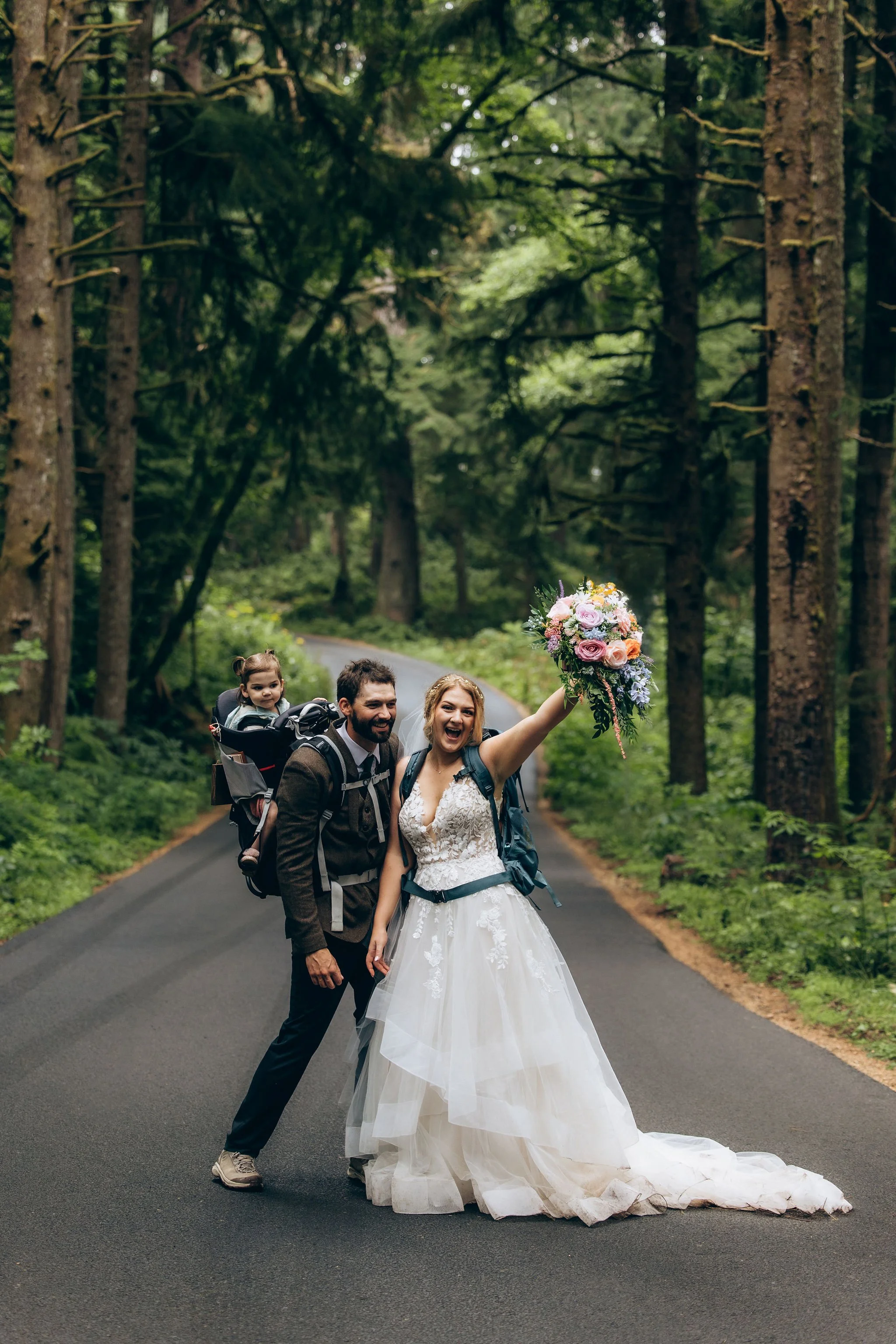 Bride wearing a comfortable elopement dress while hiking with a backpack, showing that an outdoor wedding gown can be both beautiful and practical for an adventure elopement