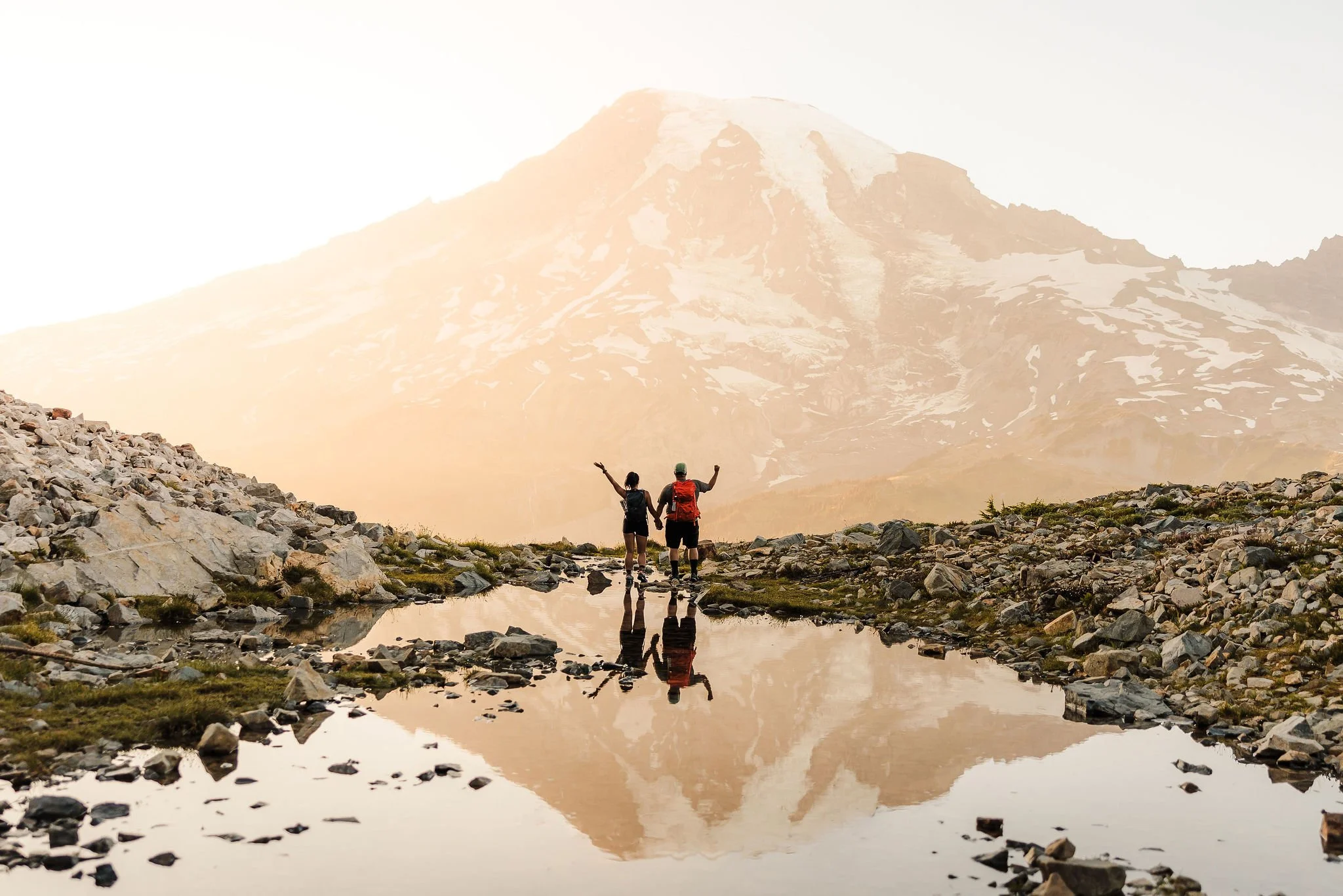 Couple hiking toward their mountain elopement location with backpacks, illustrating why it's often more comfortable to carry wedding attire and change after a longer hike