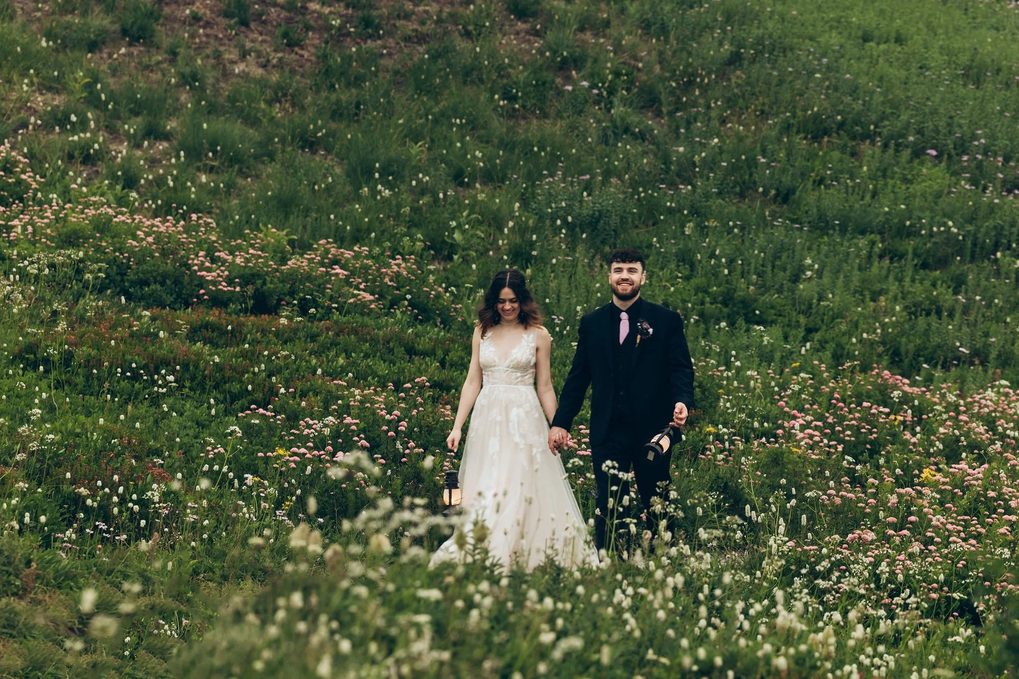 Couple walking through wildflowers during a sunset elopement on Skyline Trail at Mount Rainier National Park