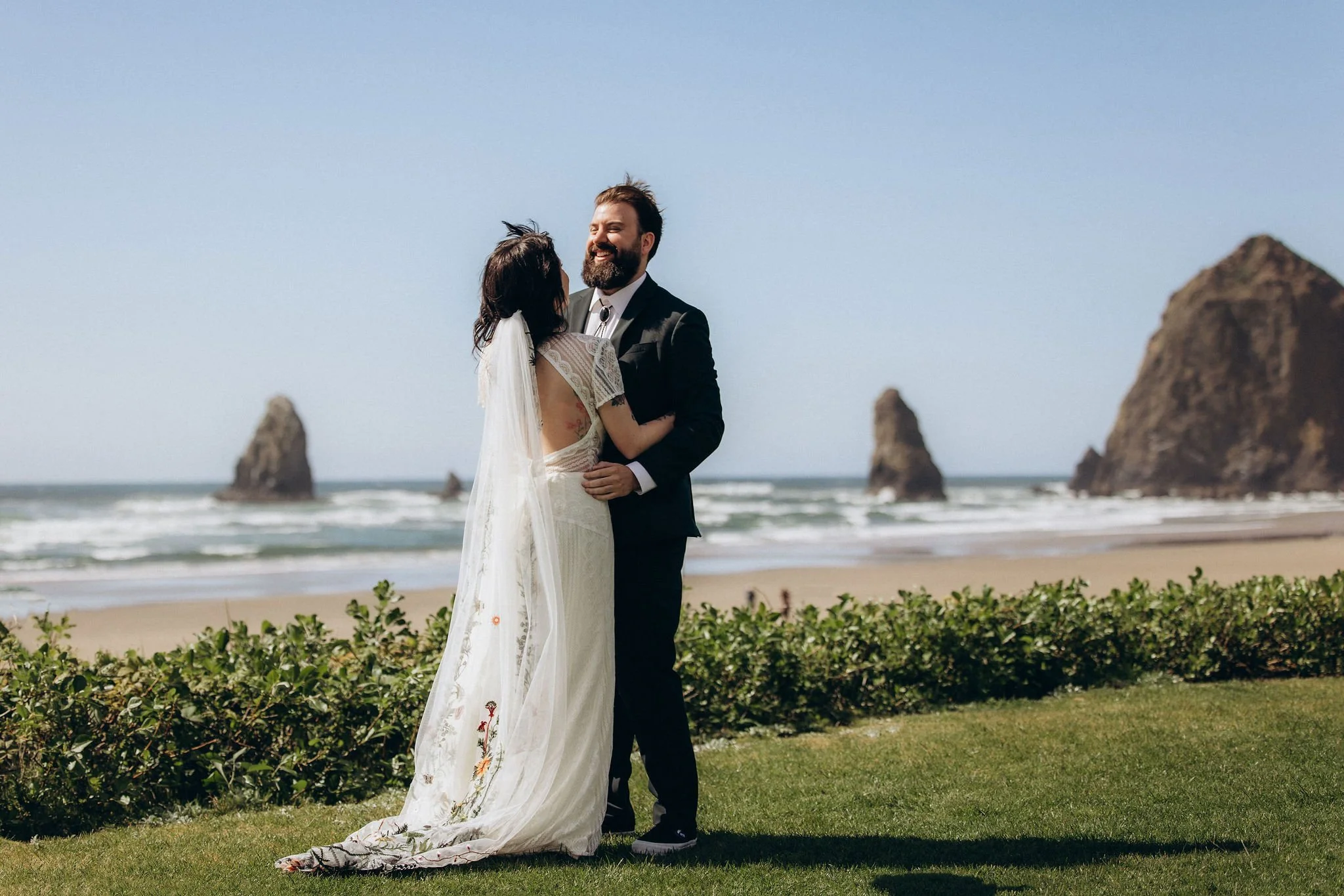 Couple sharing a first look during their elopement at Cannon Beach, Oregon, with Haystack Rock and the Pacific Ocean in the background