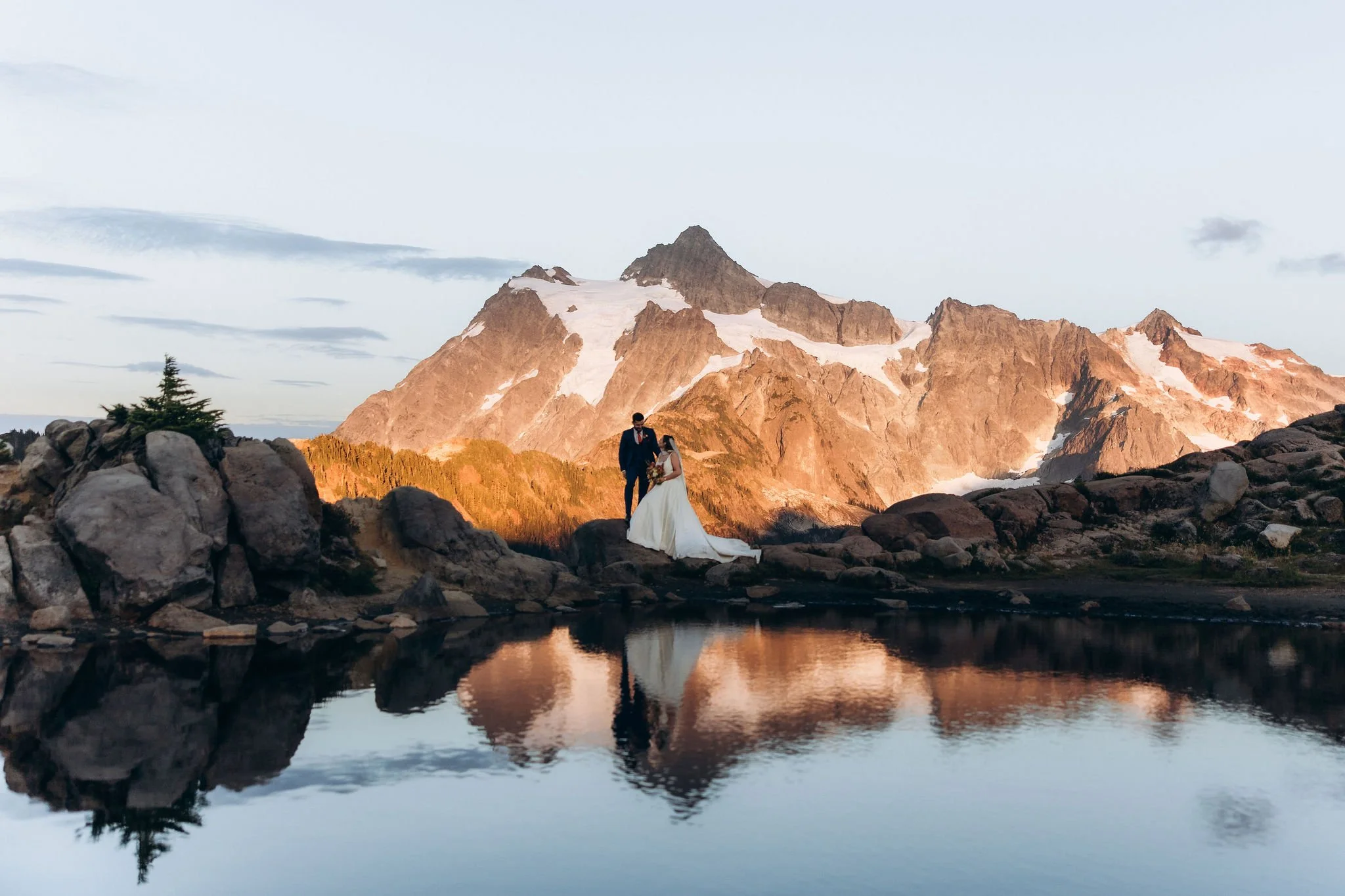 Couple standing during a Mount Baker elopement with mountain reflection in an alpine lake at sunset