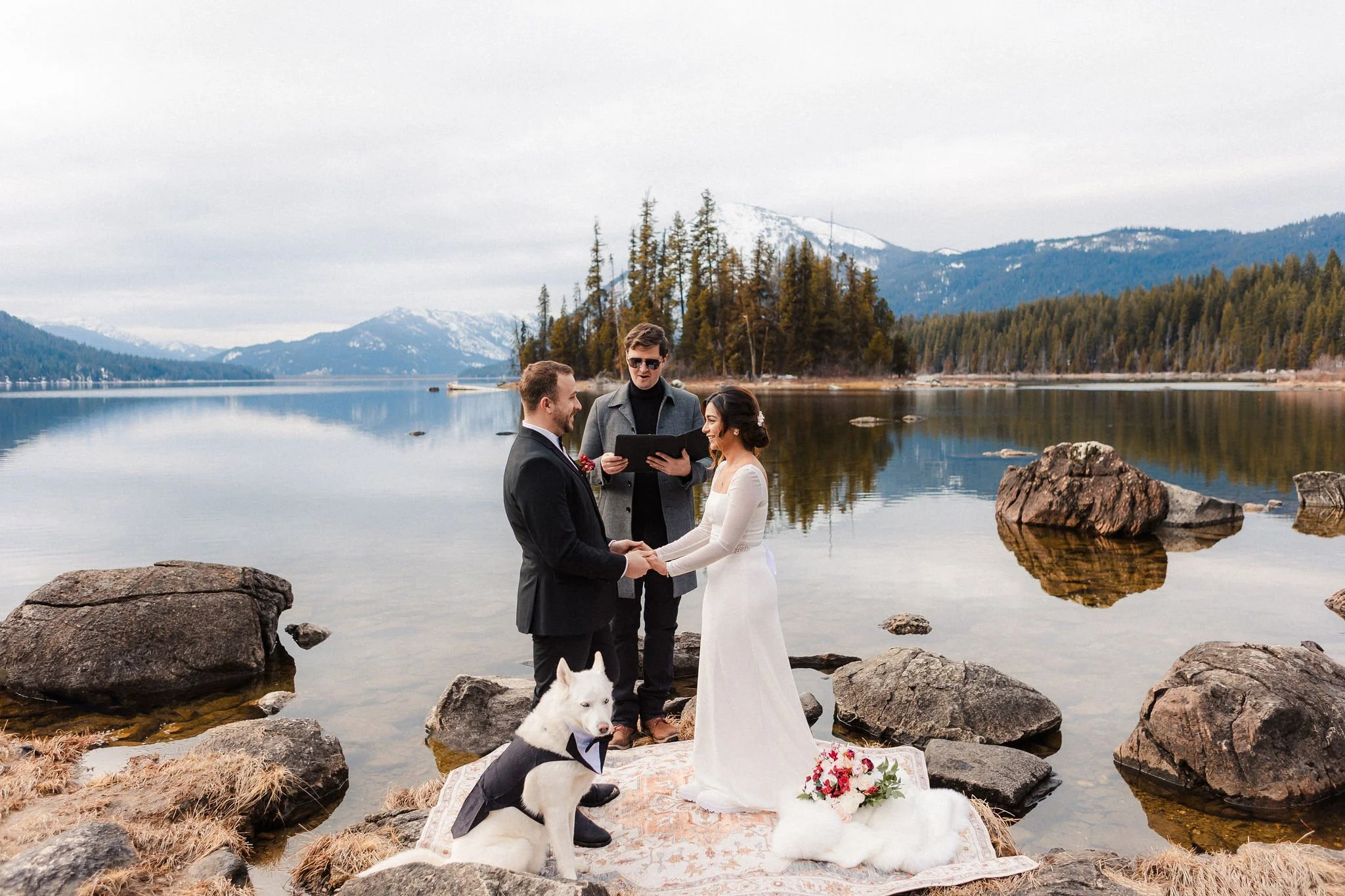 Couple exchanging vows during a spring elopement ceremony at Lake Wenatchee with their dog by the lakeshore