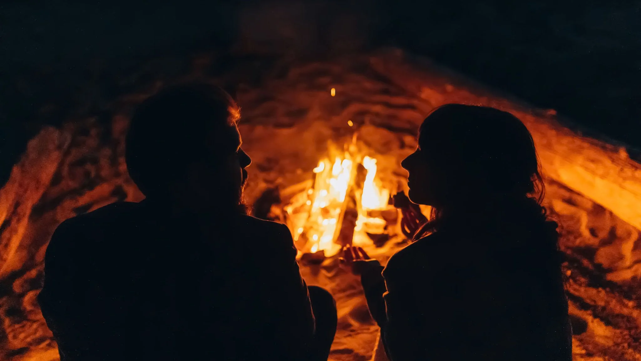 Couple sitting by a beach bonfire during an intimate elopement celebration on the Oregon Coast at night
