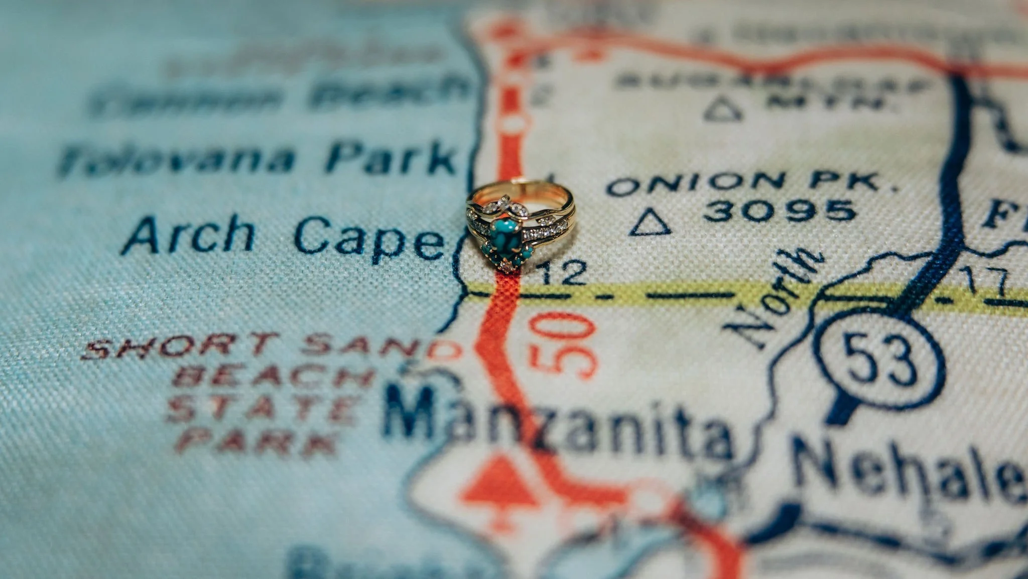 Wedding ring placed on a map of the Oregon Coast near Arch Cape and Manzanita, symbolizing an intimate coastal elopement location