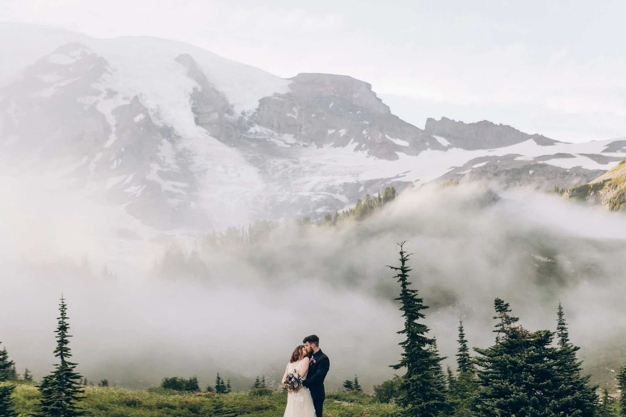 Couple eloping at Myrtle Falls in the Paradise area of Mount Rainier National Park surrounded by mist, waterfalls, and alpine scenery