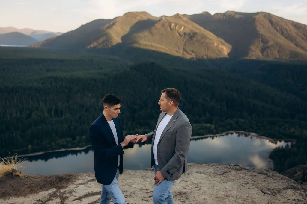 Gay couple exchanging rings during an intimate elopement at Rattlesnake Ridge, overlooking Snoqualmie Valley