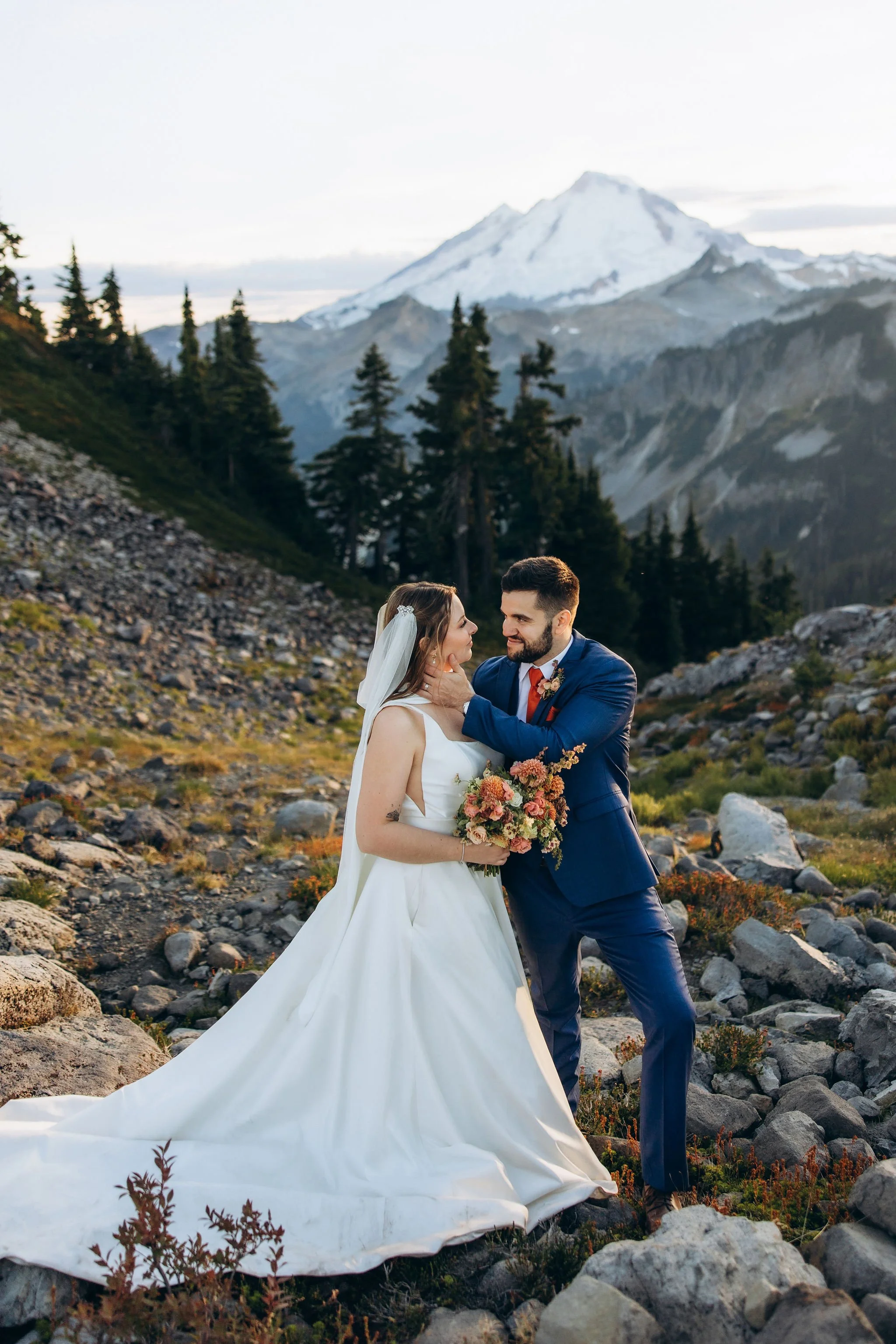 Couple embracing during an Mt Baker elopement in an alpine mountain landscape with evergreen trees and rocky terrain