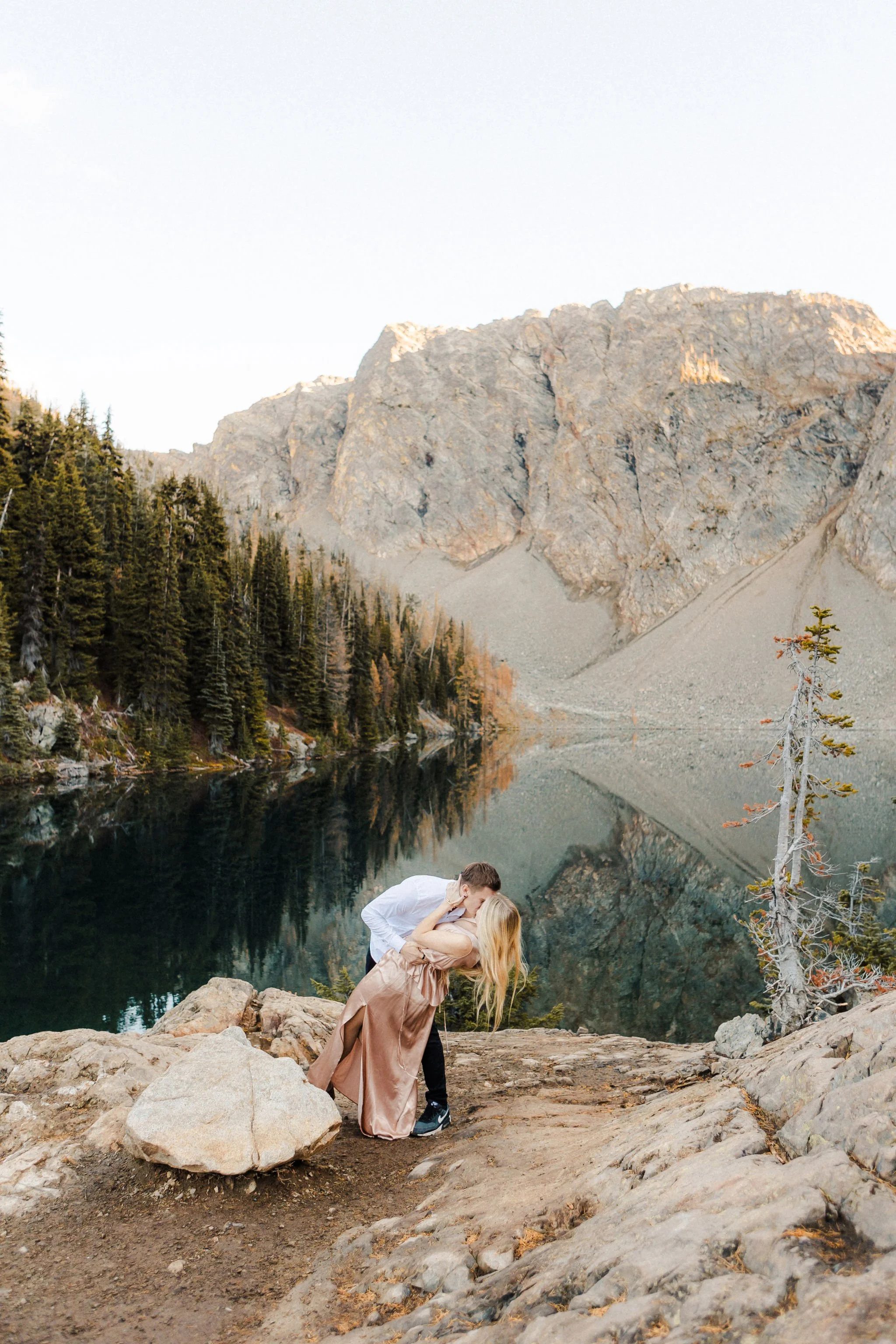 Couple sharing a kiss during a Blue Lake elopement in the North Cascades surrounded by yellow larches and mountain reflections