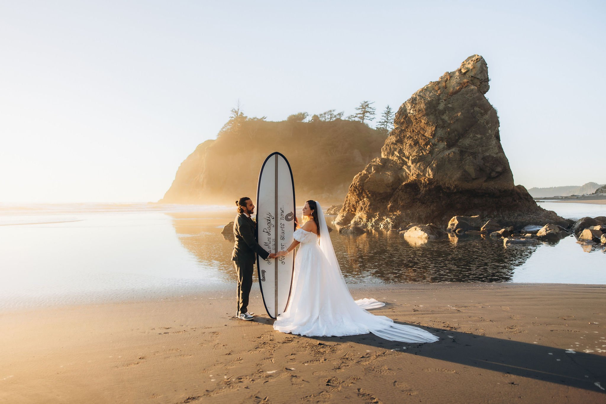 Surf-inspired elopement at Ruby Beach in Olympic National Park at sunset with couple holding a surfboard
