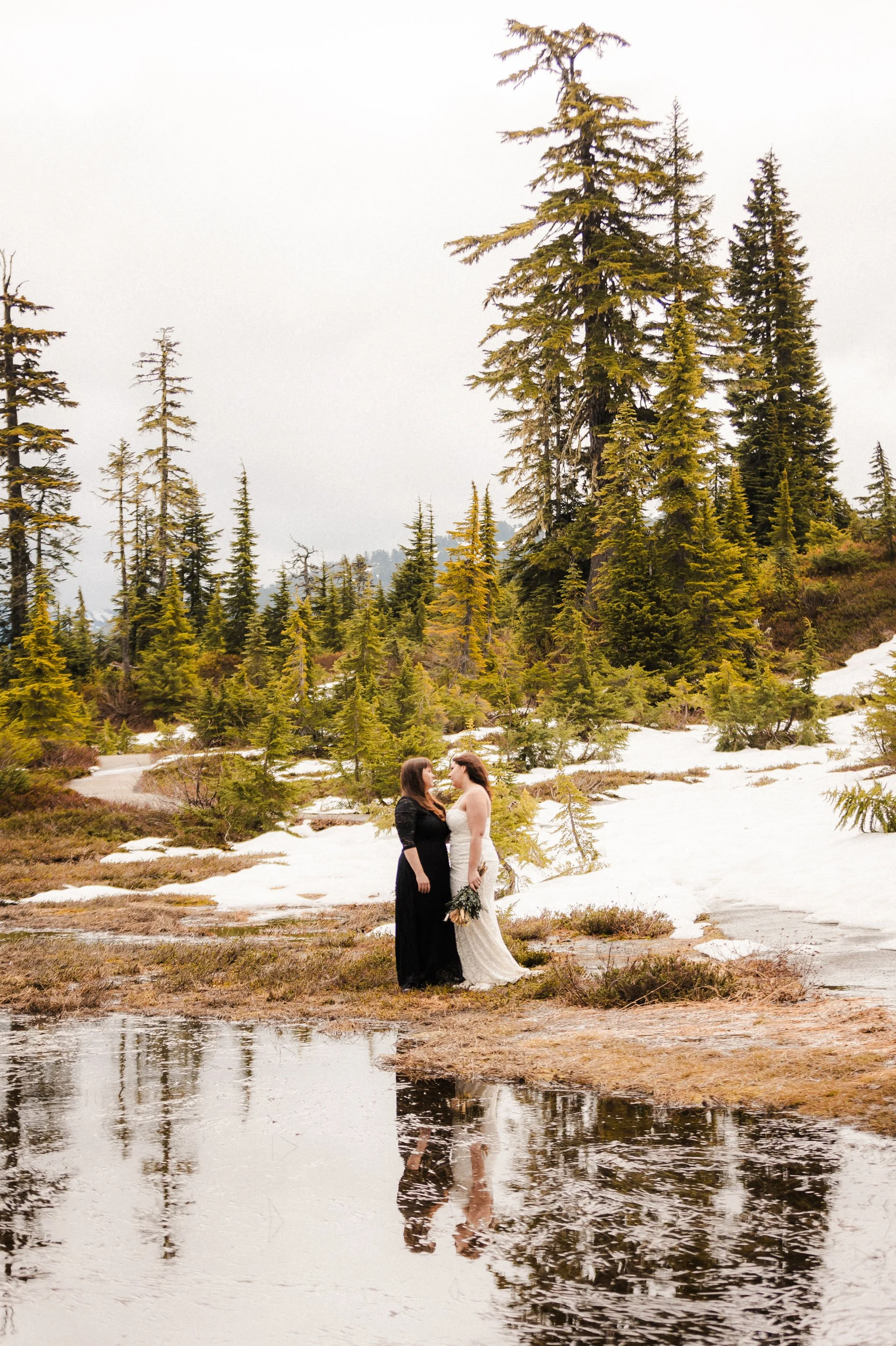 LGBT couple standing together during a Picture Lake spring elopement with snow and reflections in the Mount Baker area