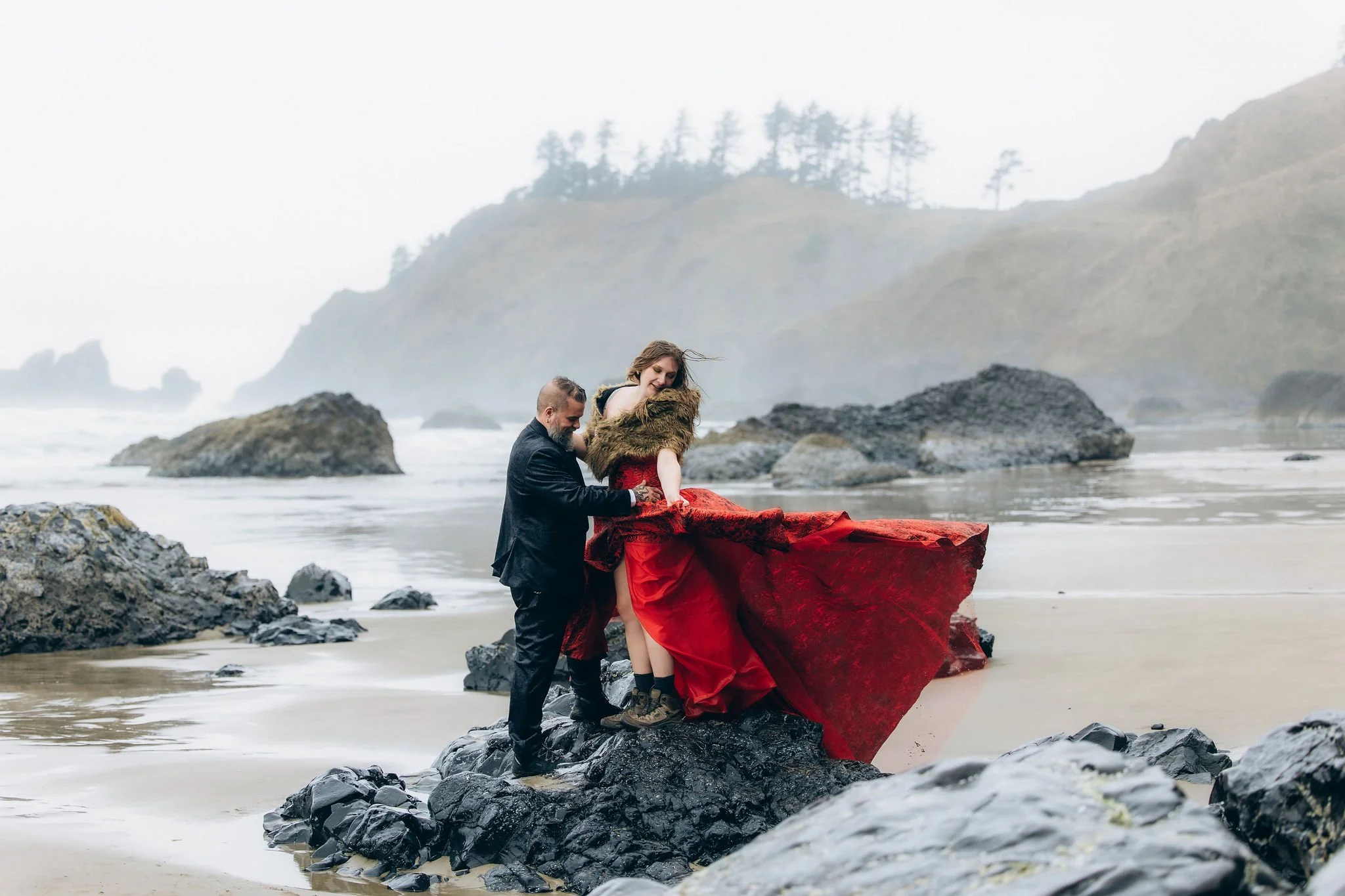 Couple sharing a winter elopement moment at Crescent Beach in Ecola State Park on the Oregon Coast with a flowing red elopement dress