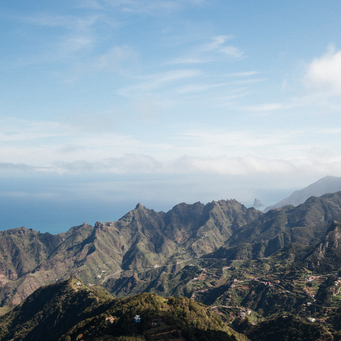 Paysage de montagnes verdoyantes avec villages dispersés, ciel bleu avec quelques nuages, paysages montagneux dans le lointain