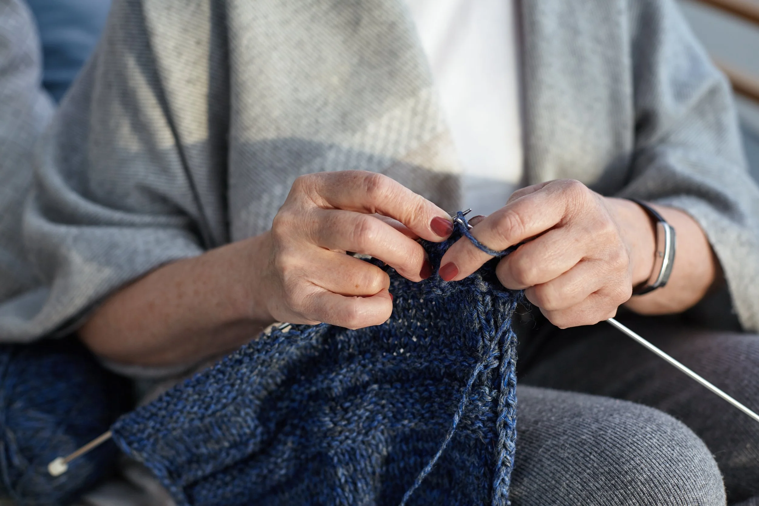 unrecognizable-elderly-senior-woman-wearing-wide-gray-scarf-wrist-watch-knitting-sweater-close-up-view-aged-female-hands-holding-needles-yarn-doing-needlework-selective-focus.jpg