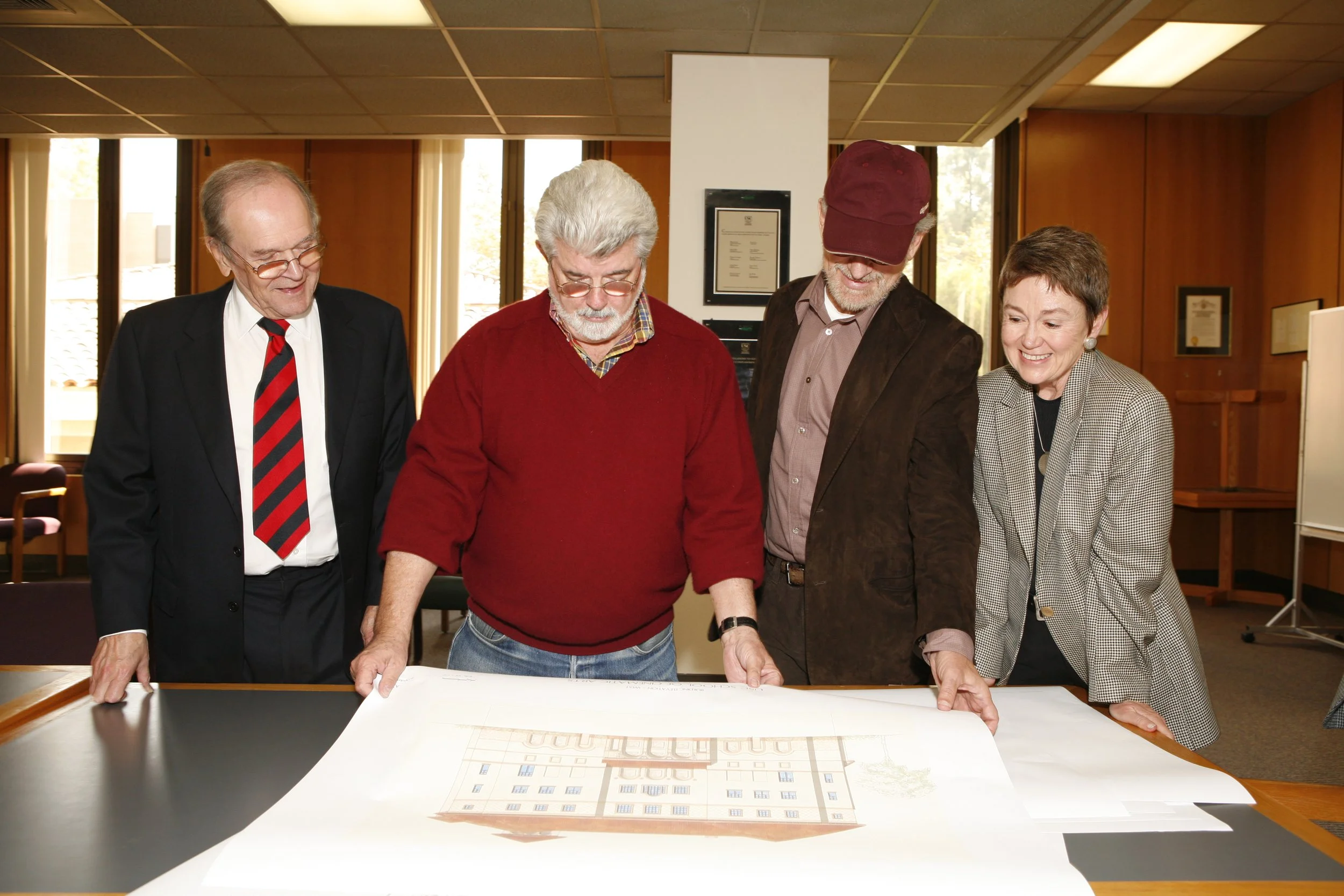 Price looks over plans for the new School of Cinematic Arts Complex with Dean Elizabeth Daley, George Lucas, and Steven Spielberg.