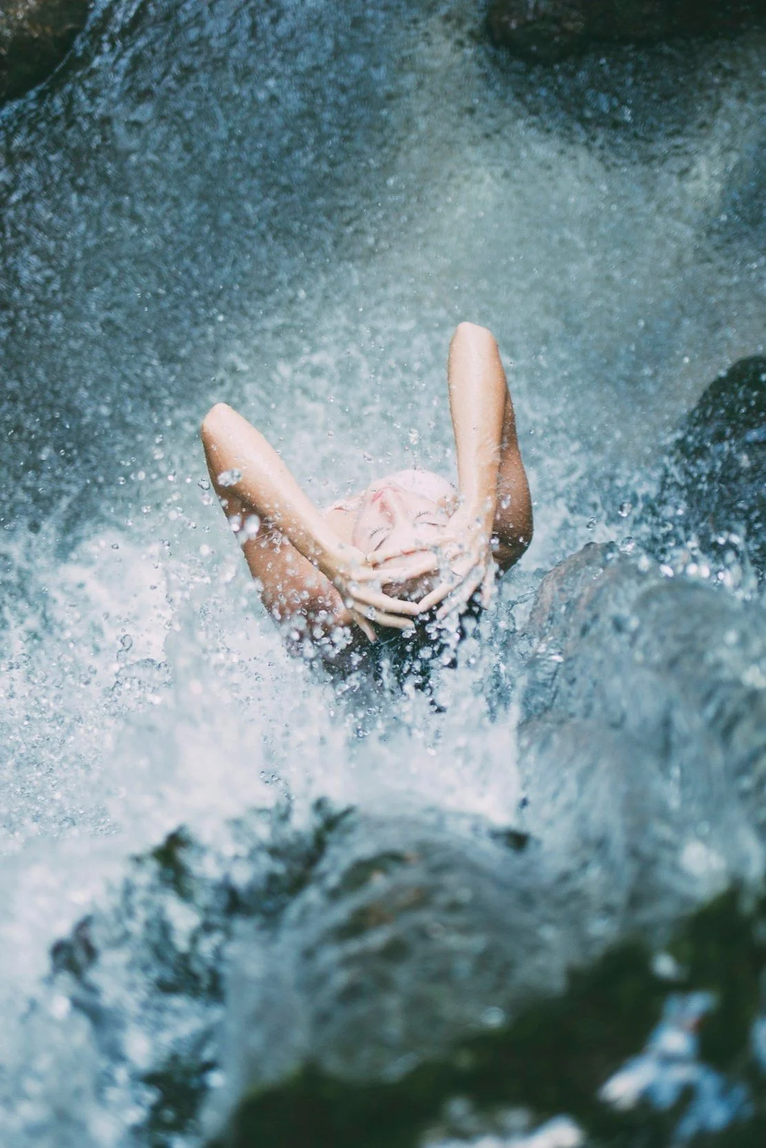 Person swimming in a river, face partially submerged, with water splashing around.
