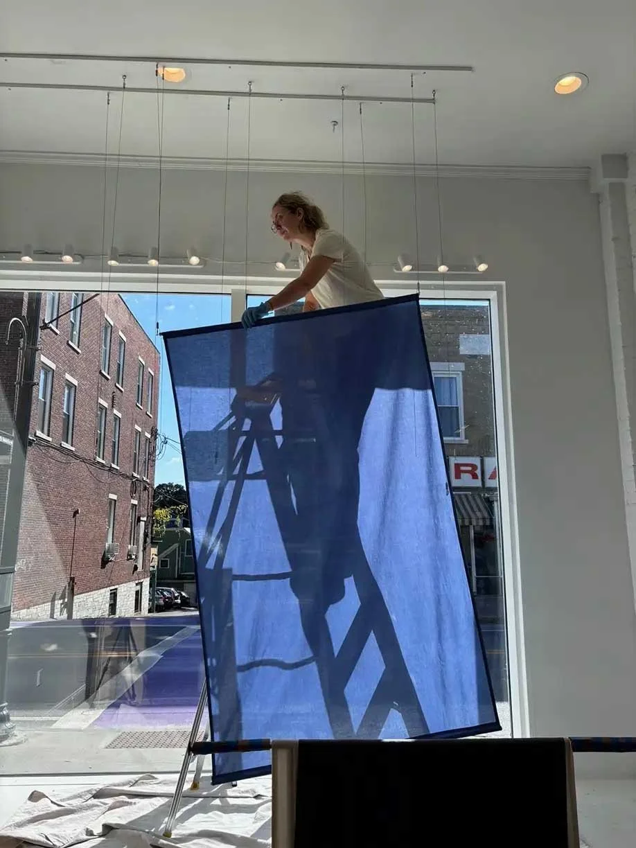 Kate hanging blue translucent fabric panel on ladder