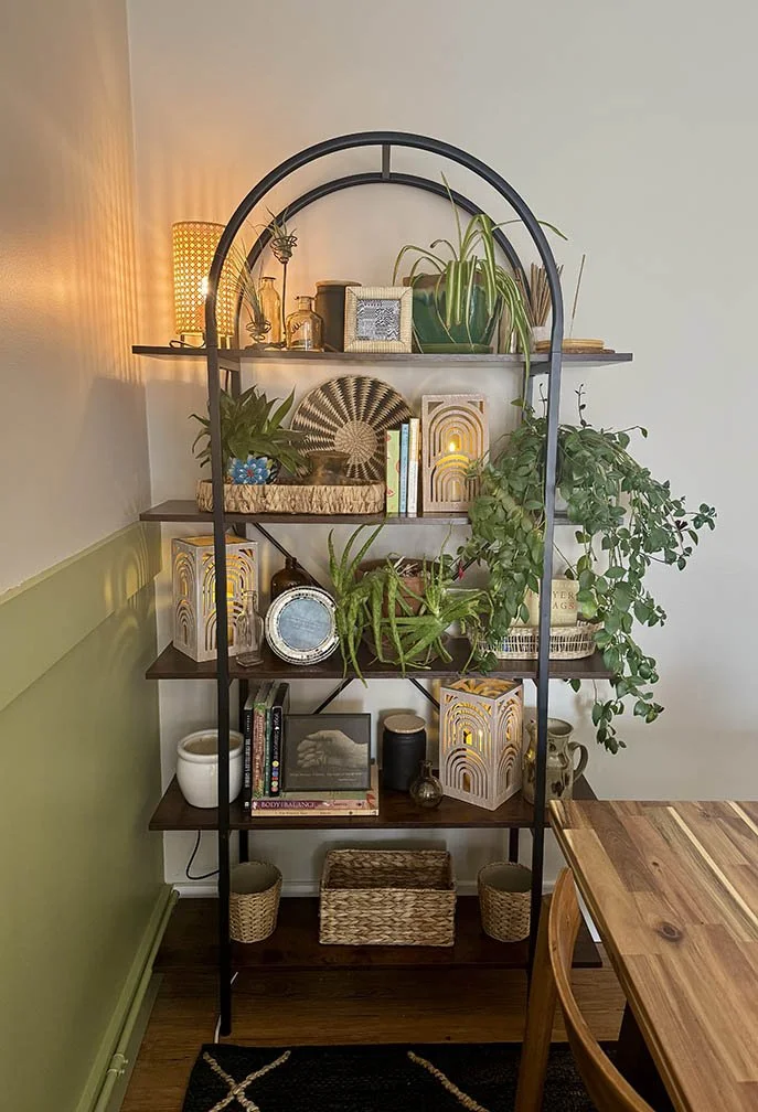closeup of bookshelf styled with plants and lanterns
