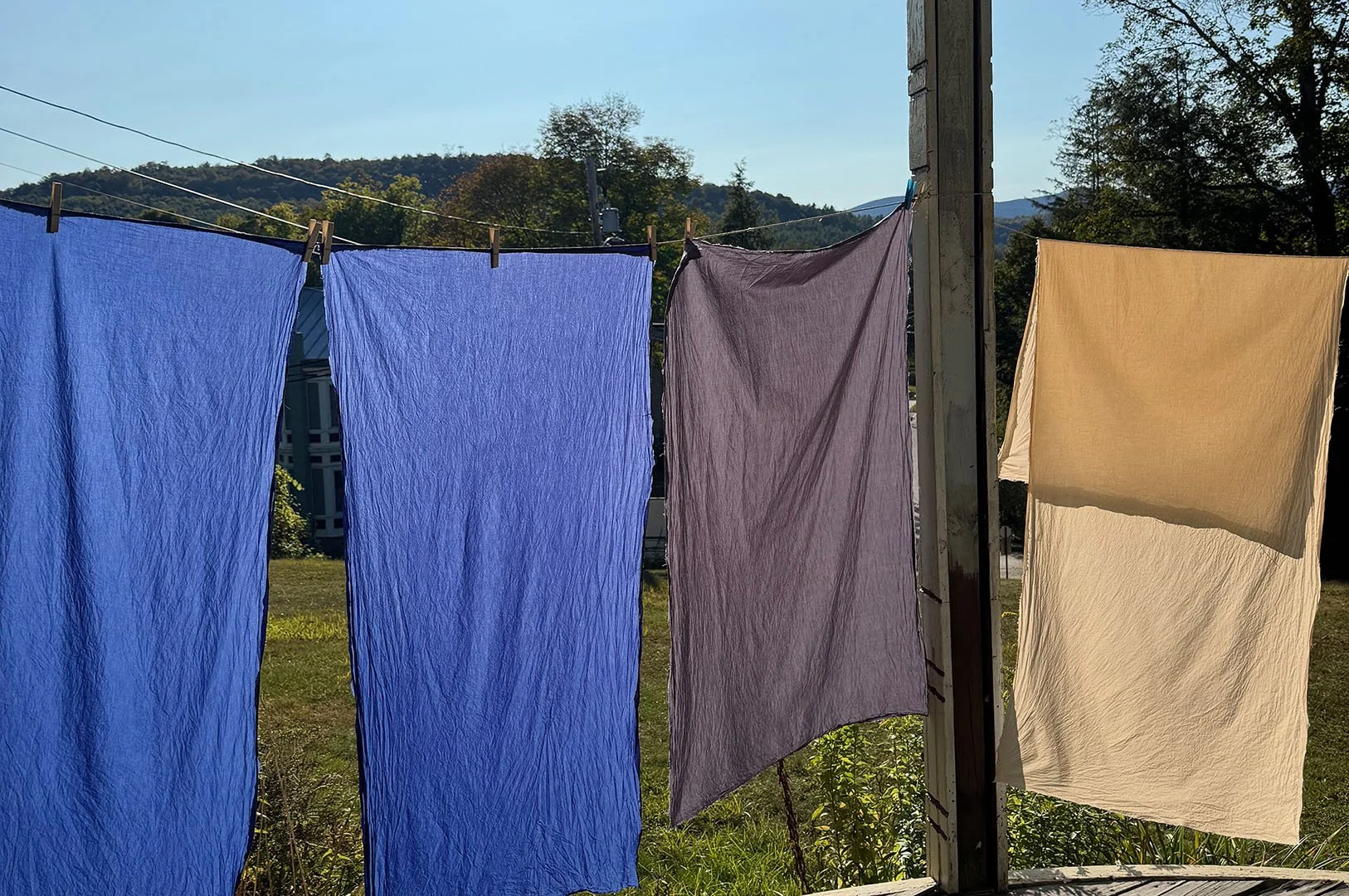 freshly dyed fabric drying on clothes lines outside of the studio on a sunny day