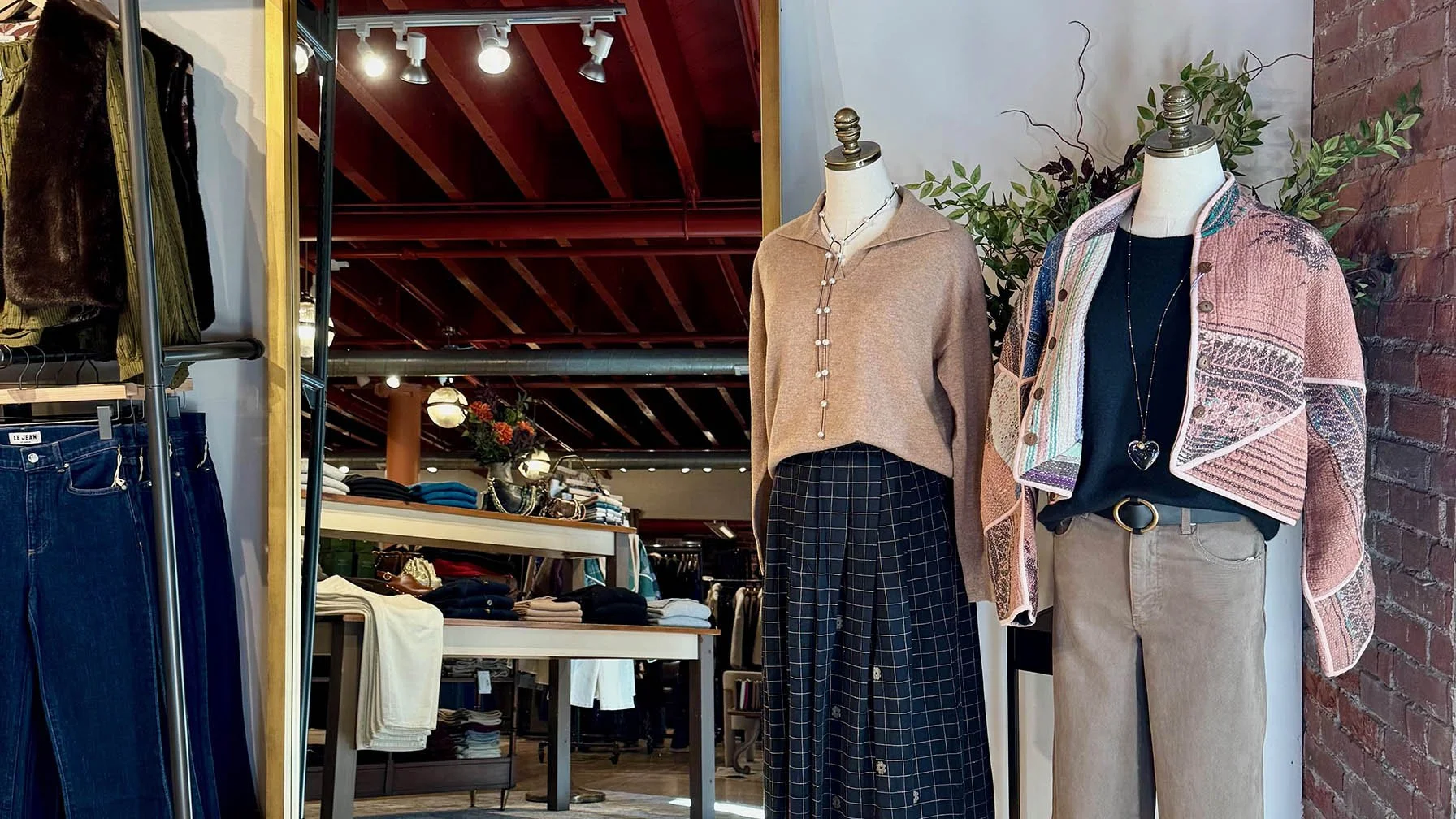 two female mannequins dressed in neutral fall outfits in front of a large floor mirror