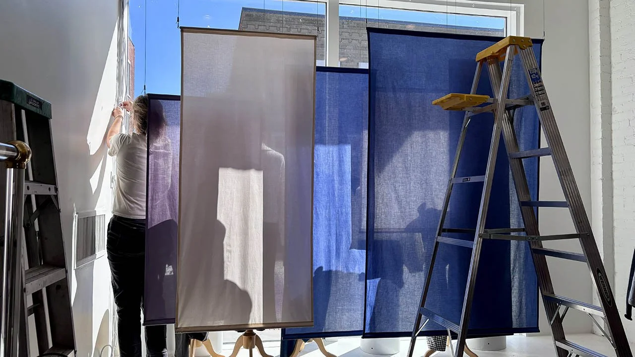 woman installing a window display of blue and white fabric panels