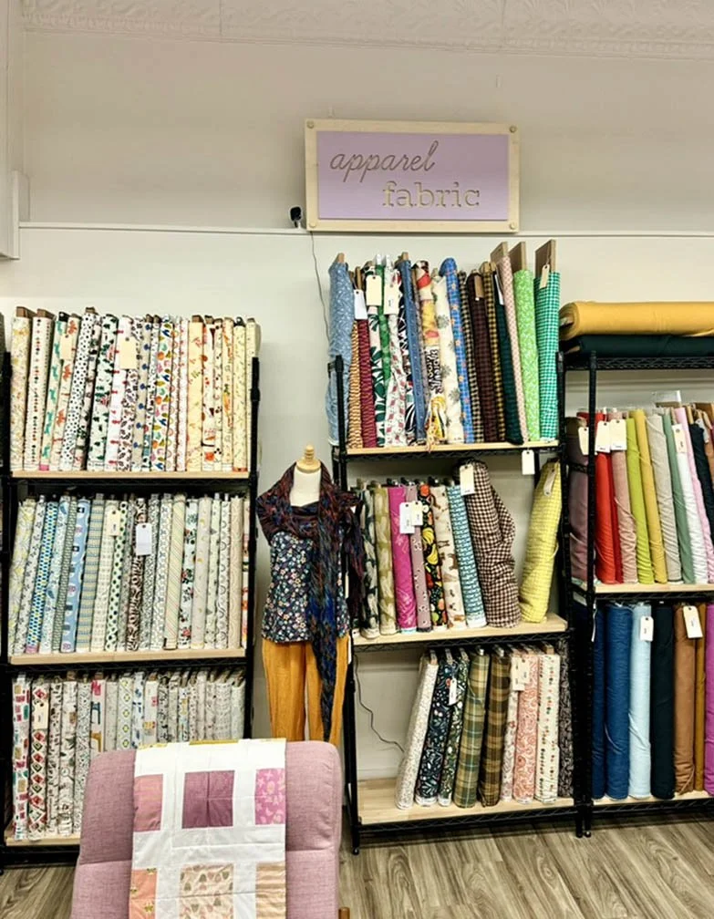 apparel fabric sign above shelving of fabric bolts