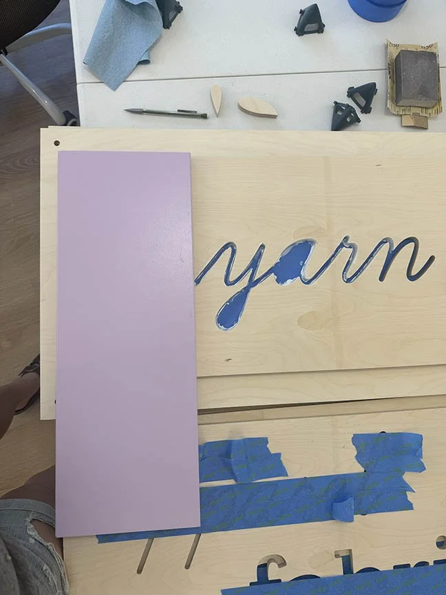 studio process of color analysis while taping and painting the yarn sign