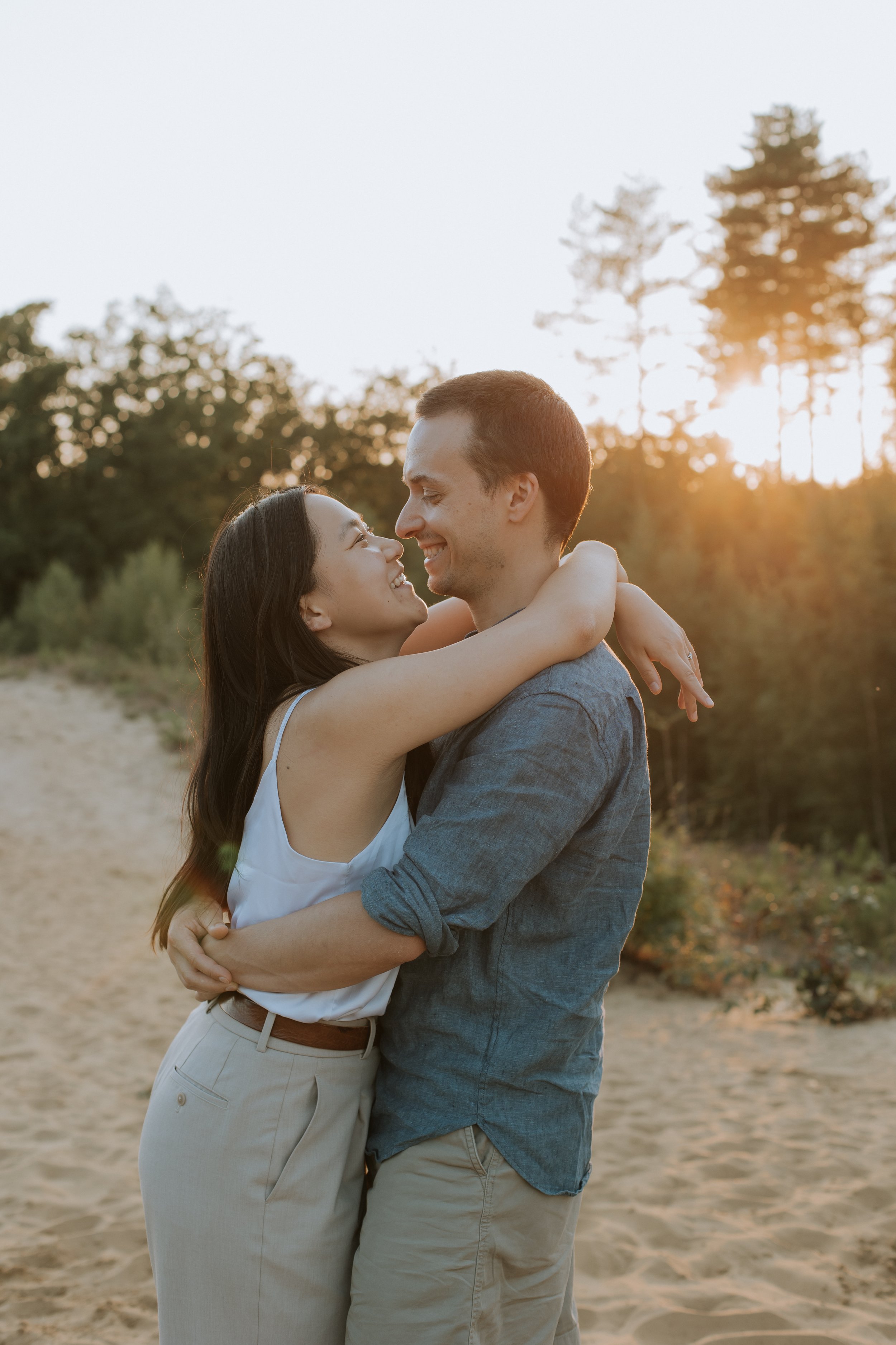 Een koppel omhelst elkaar liefdevol tijdens de zonsondergang in het zand in Averbode.