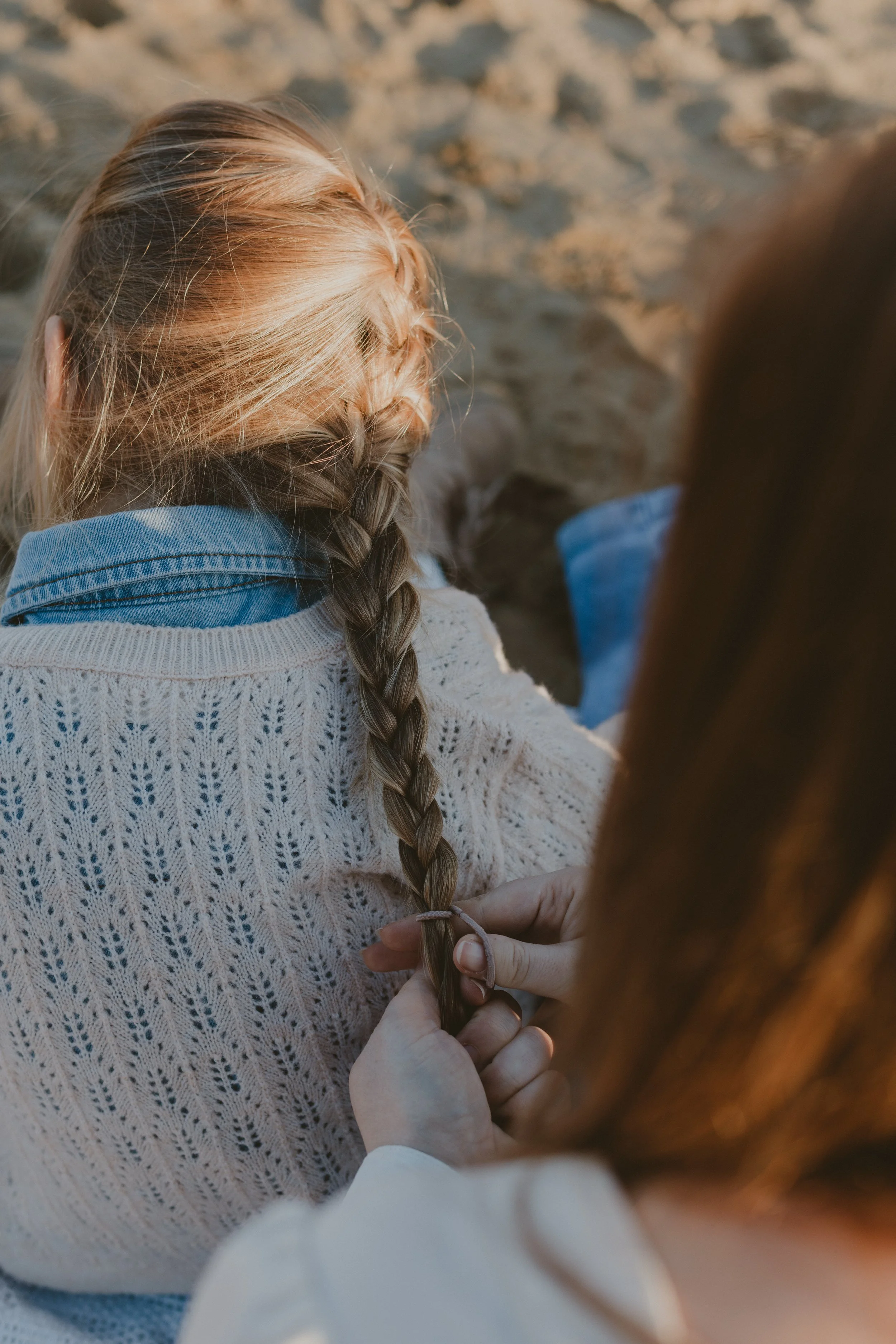 mama vlecht dochter haar haar tijdens een gezinsshoot in Vlaams-Brabant