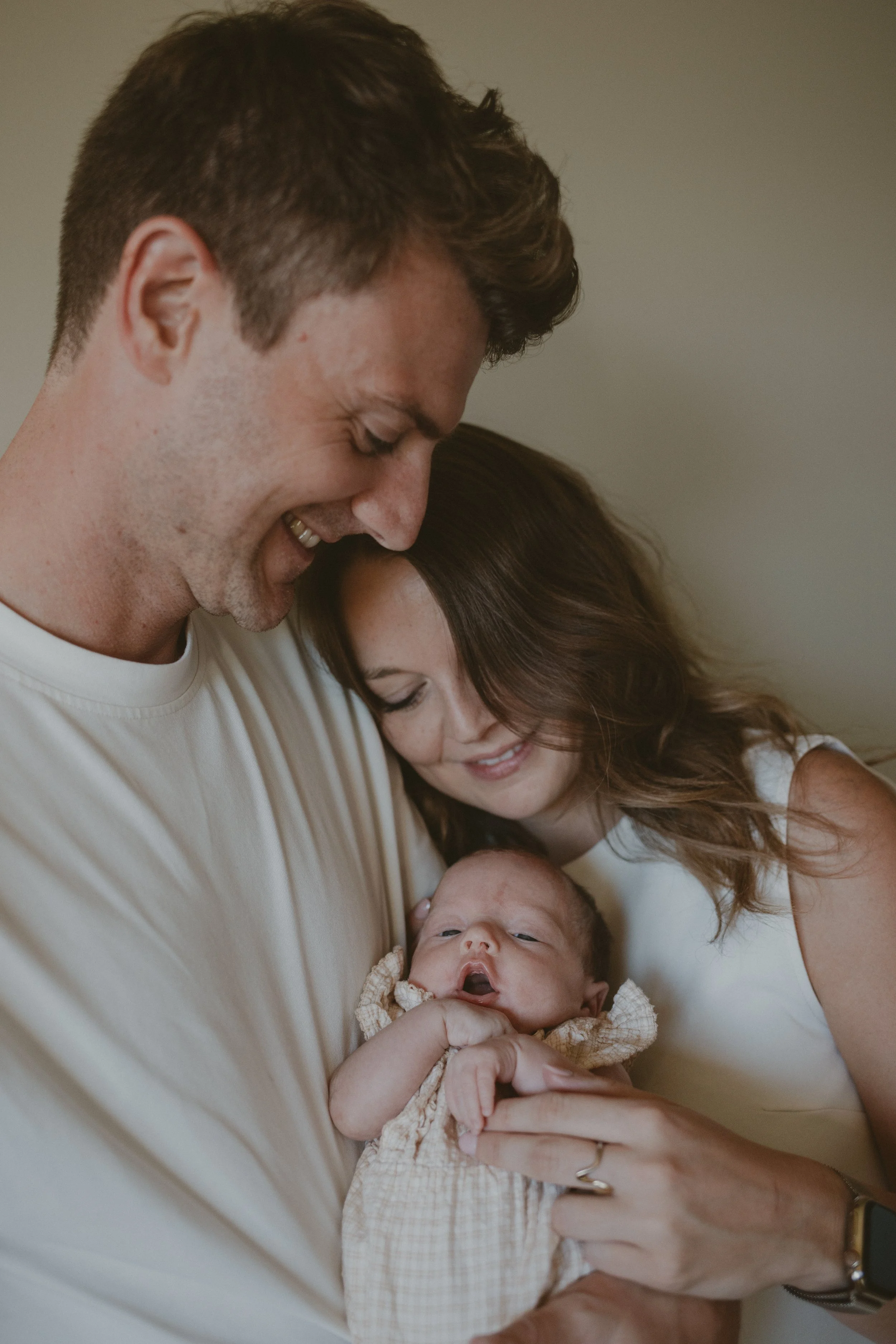Mama en papa houden al knuffelend hun newborn baby vast.