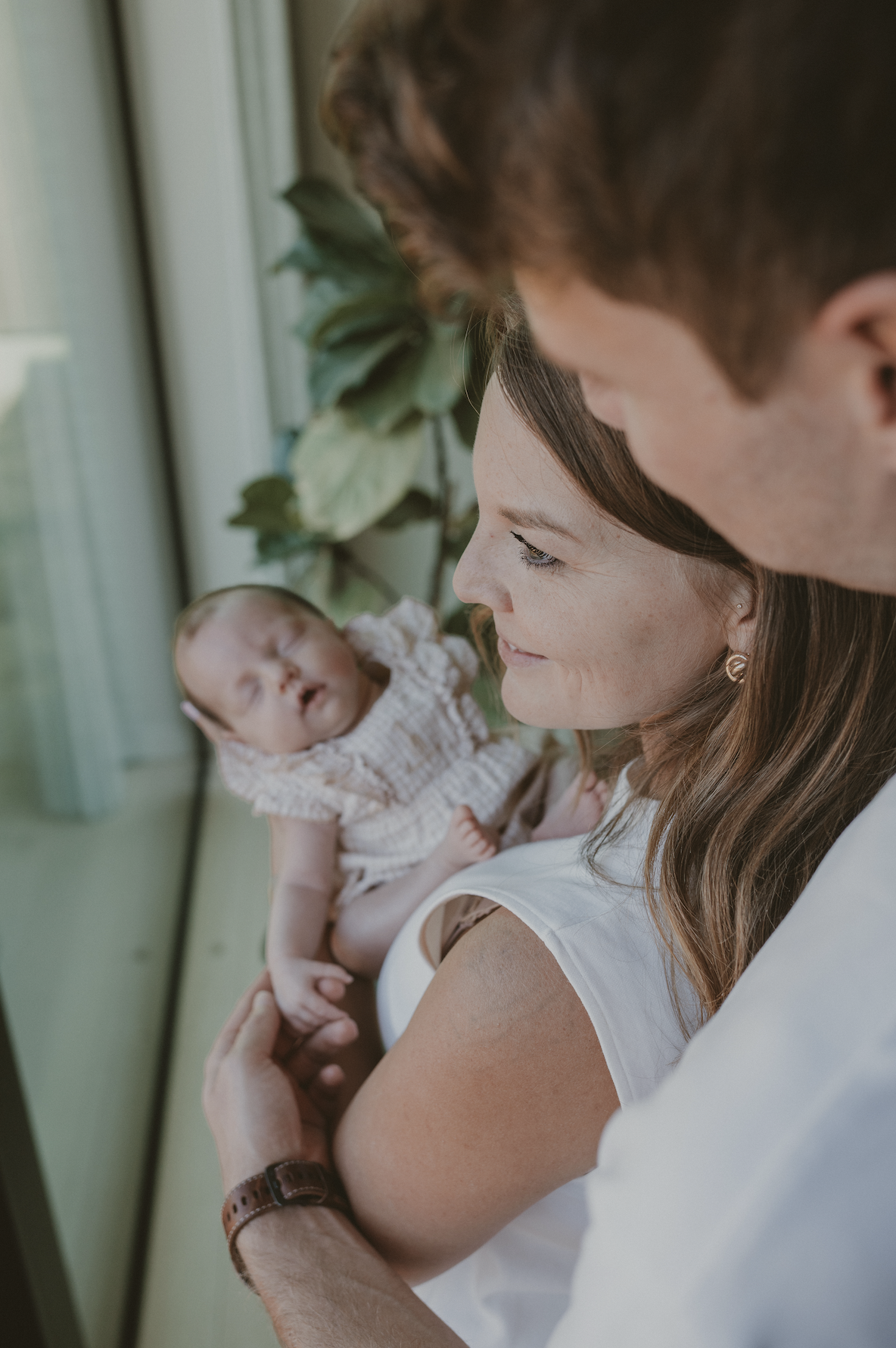 mama en papa knuffelen hun pasgeboren dochtertje tijdens de newborn fotoshoot.