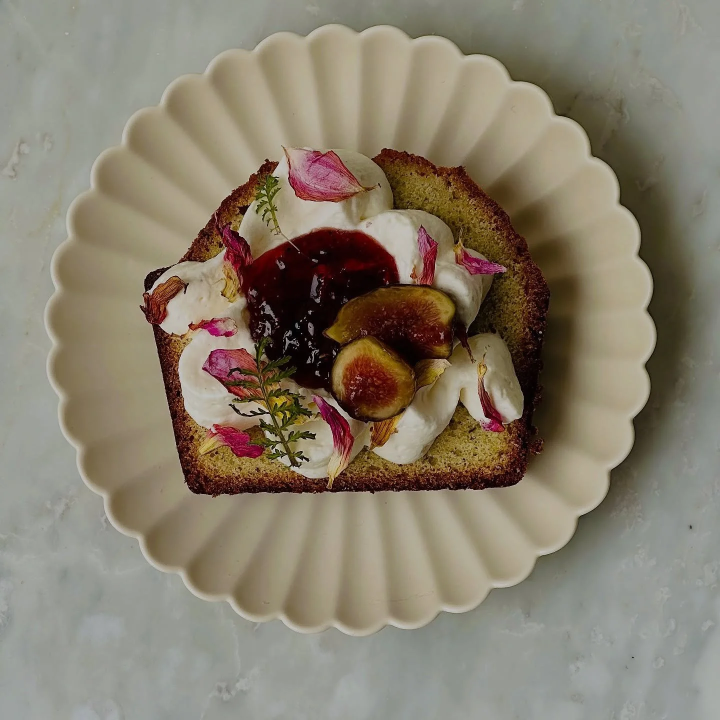 DAHLIA TEA CAKE

A deeply aromatic french tarragon and meyer lemon&ndash;infused pound cake, lush with aromatic oils and a tender crumb that melts into a whisper of warmth from Urfa Chile pepper kissed dahlia petal preserve. Topped with citrus lace h
