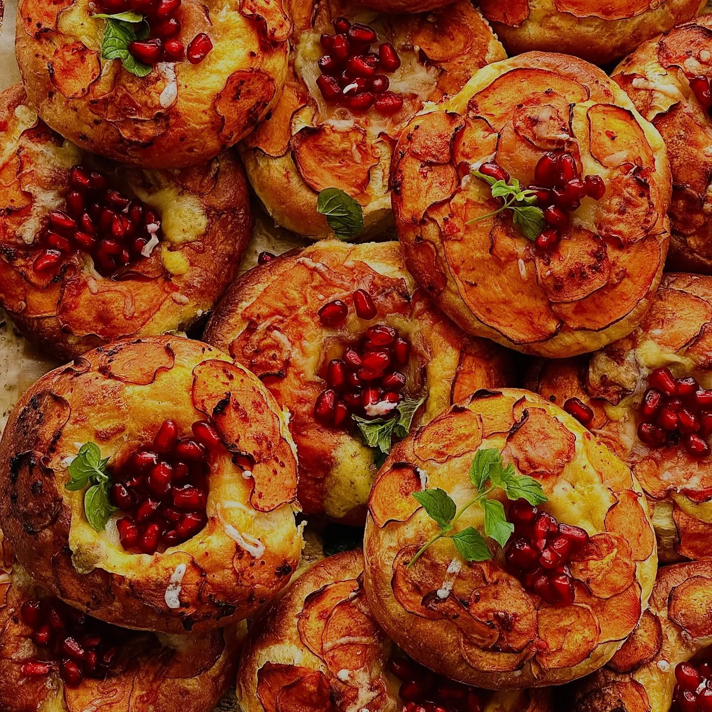 HARISSA SWEET POTATO POMEGRANATE BUN

A symphony of heat, cream, and brightness &mdash; these golden sweet potato buns are filled with a spiced b&eacute;chamel, harissa-honey glazed sweet potato discs, and melted Gruy&egrave;re. Finished with a kiss 
