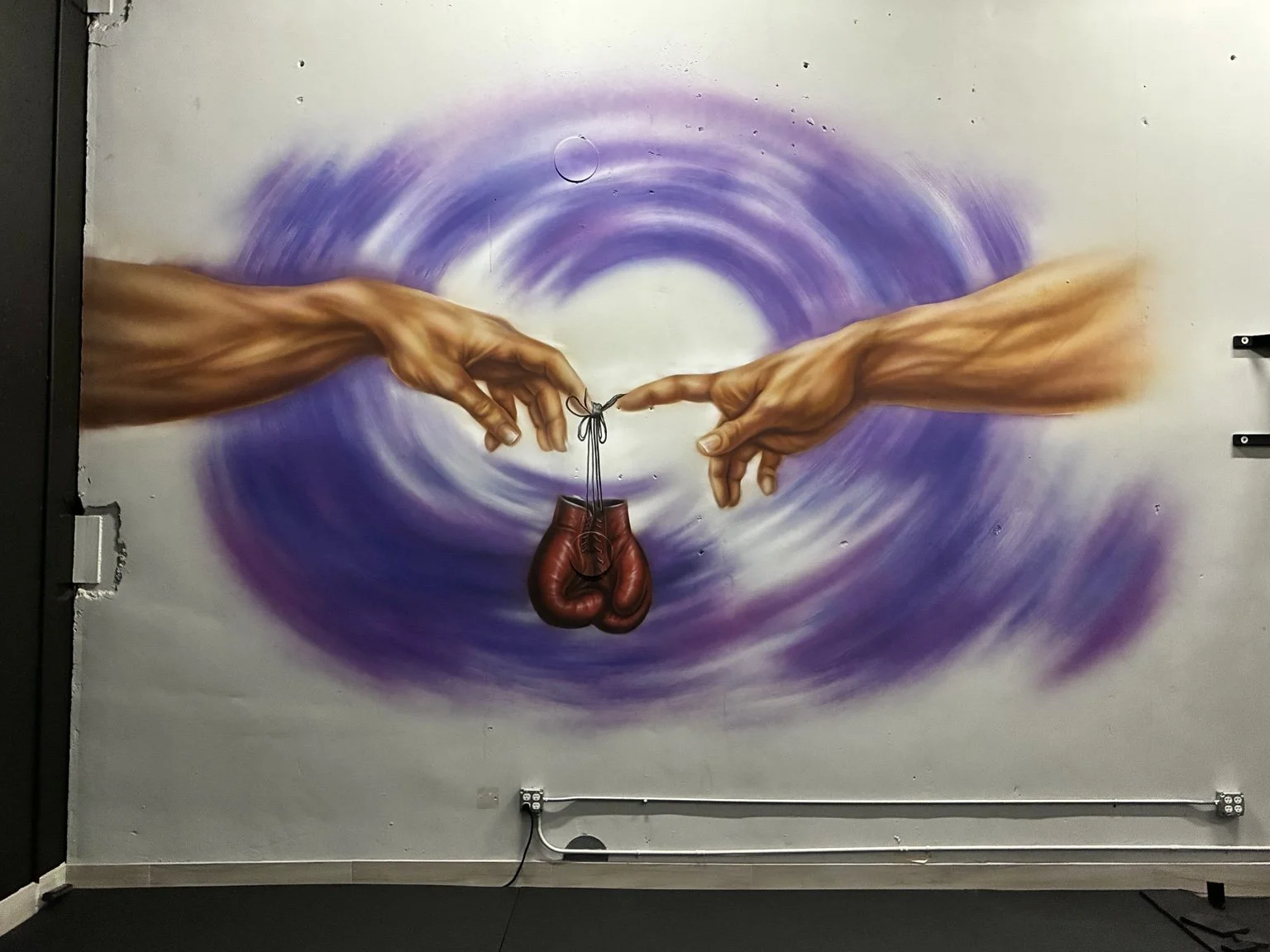 Michelangelo-inspired hands holding red boxing gloves against purple circles, custom MMA gym mural by Art by Nargiza