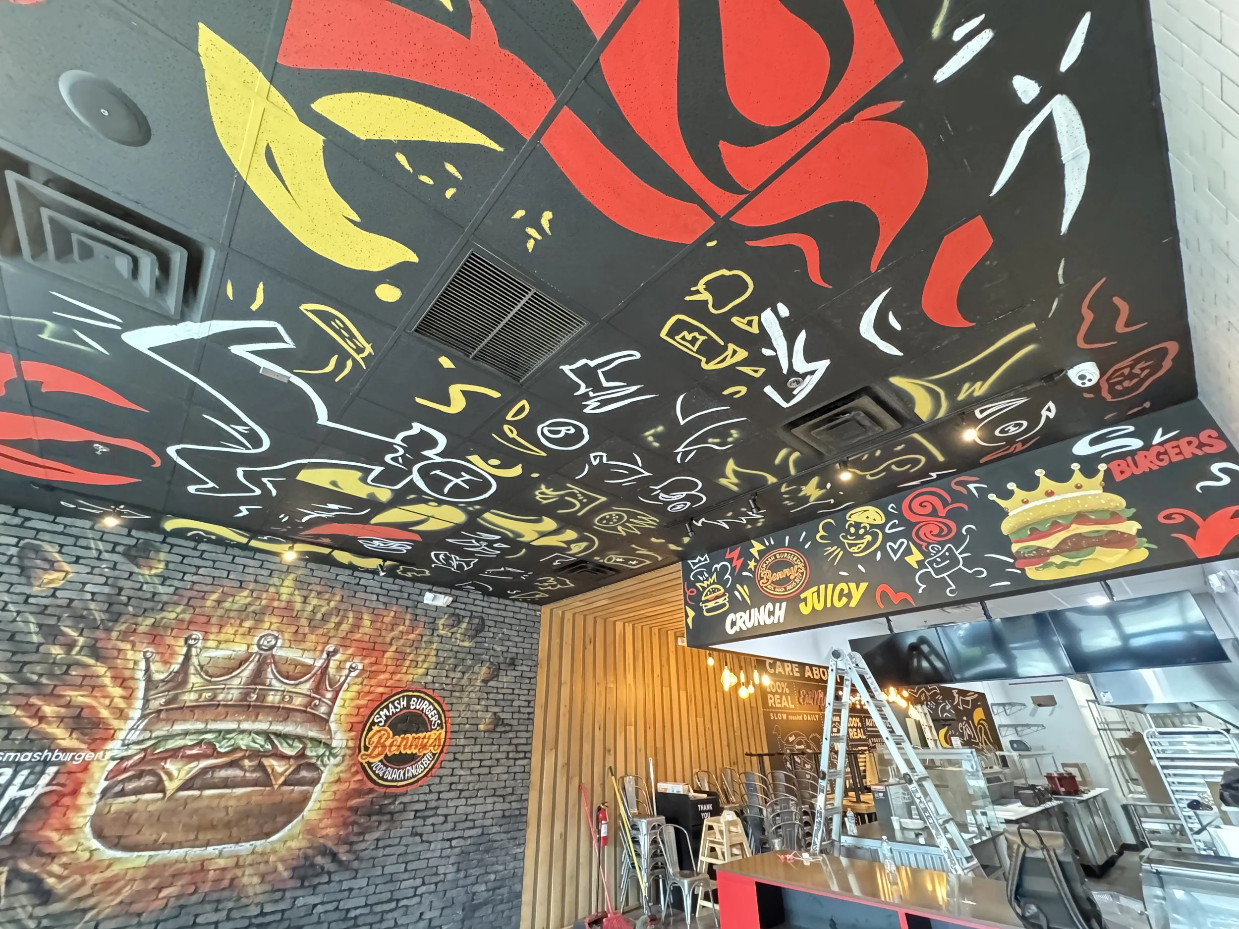 Black, red and yellow branded mural covering a restaurant wall and ceiling