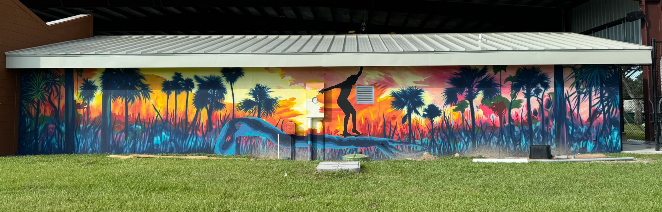 Florida sports facility mural with a colorful sunset and athlete silhouette