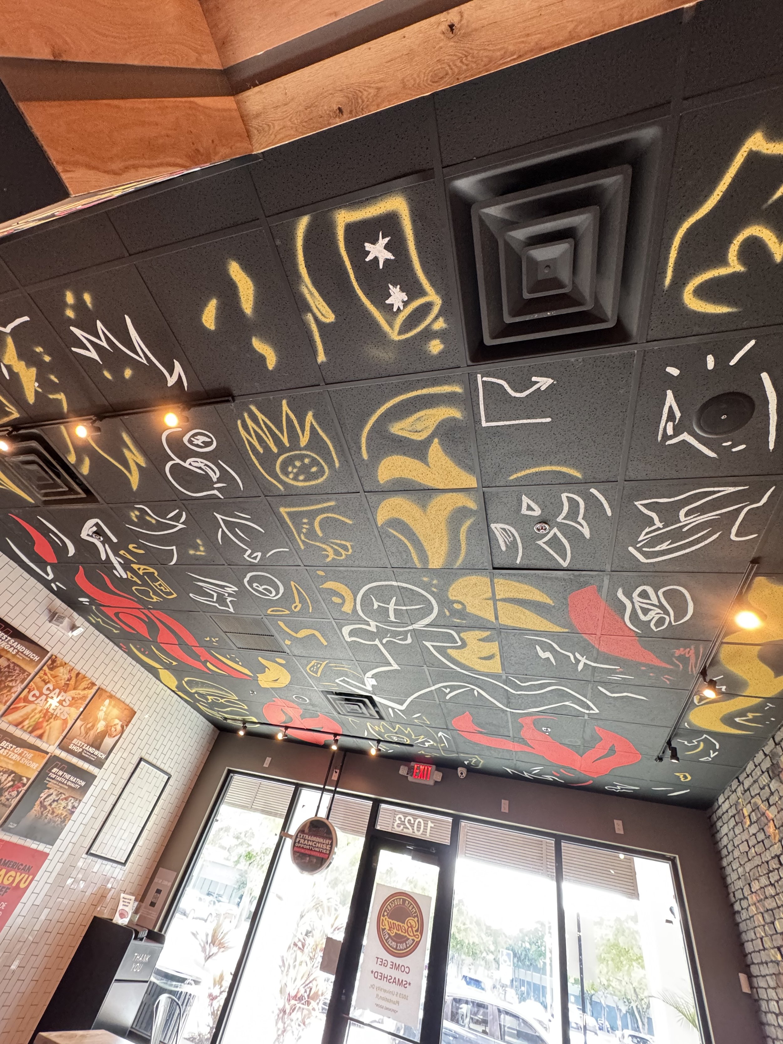 Hand-painted restaurant ceiling mural with playful food-inspired line art