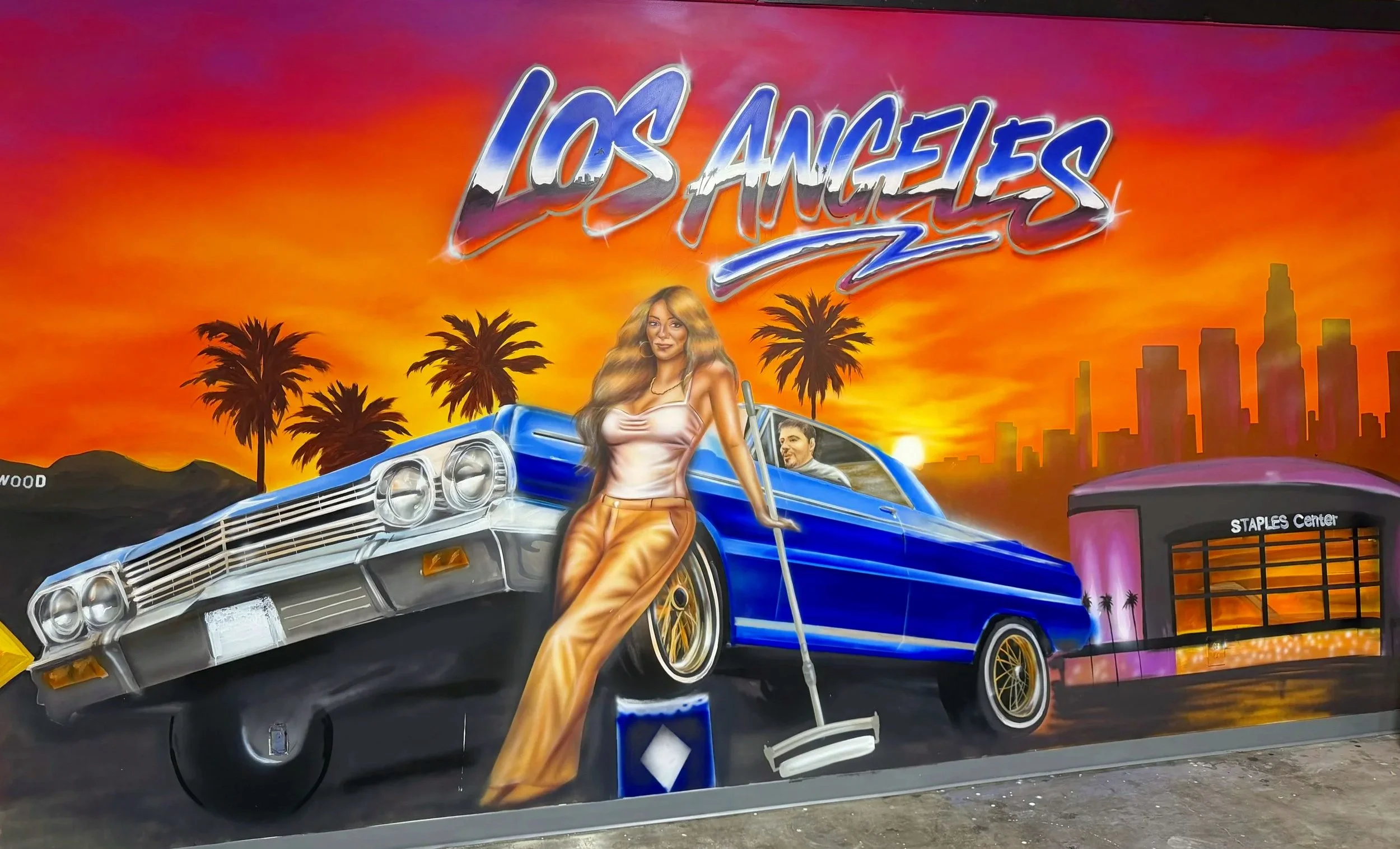 Los Angeles showroom mural with a classic blue car, city skyline and sunset by Art by Nargiza