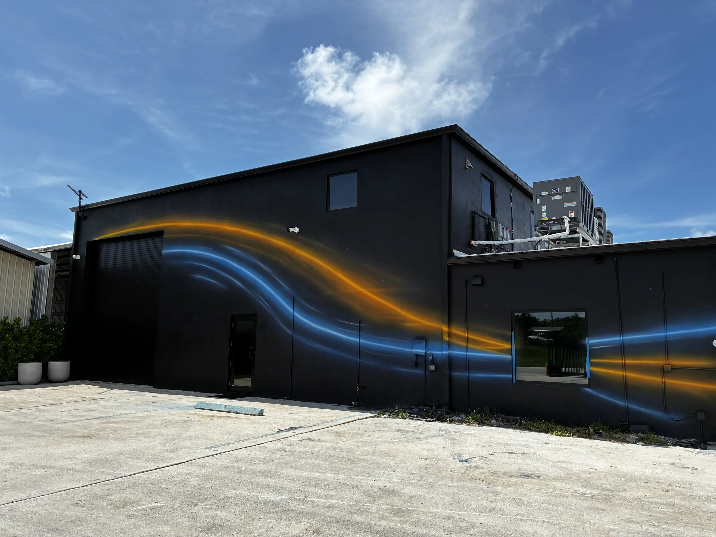 Minimal blue and orange light-trail mural across a black commercial facade
