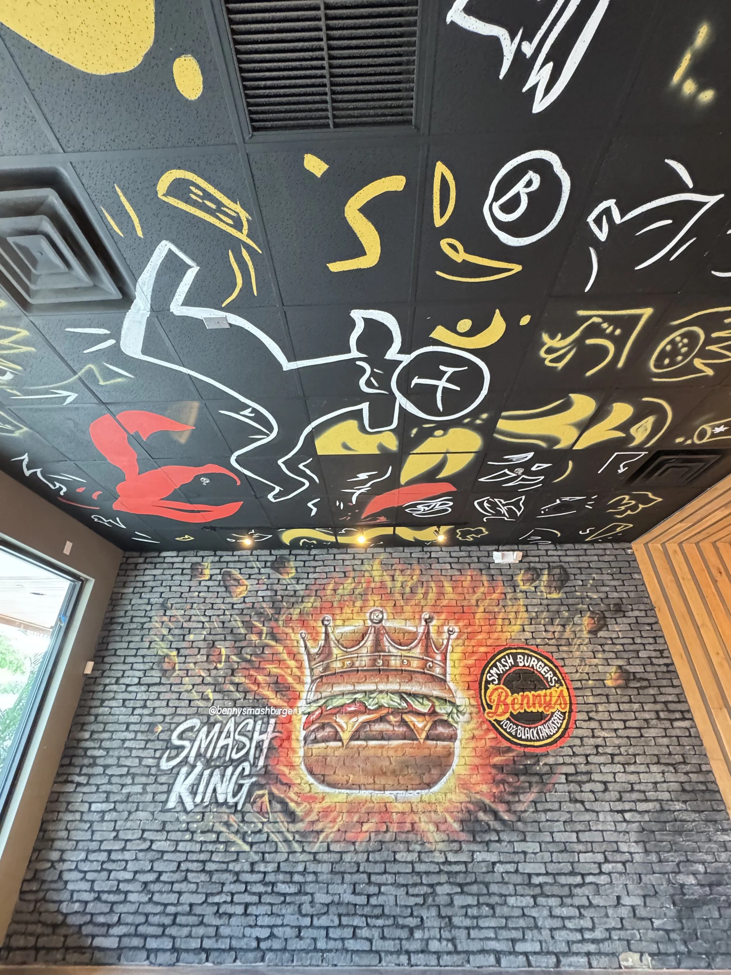 Restaurant mural with a flaming burger and hand-painted ceiling graphics