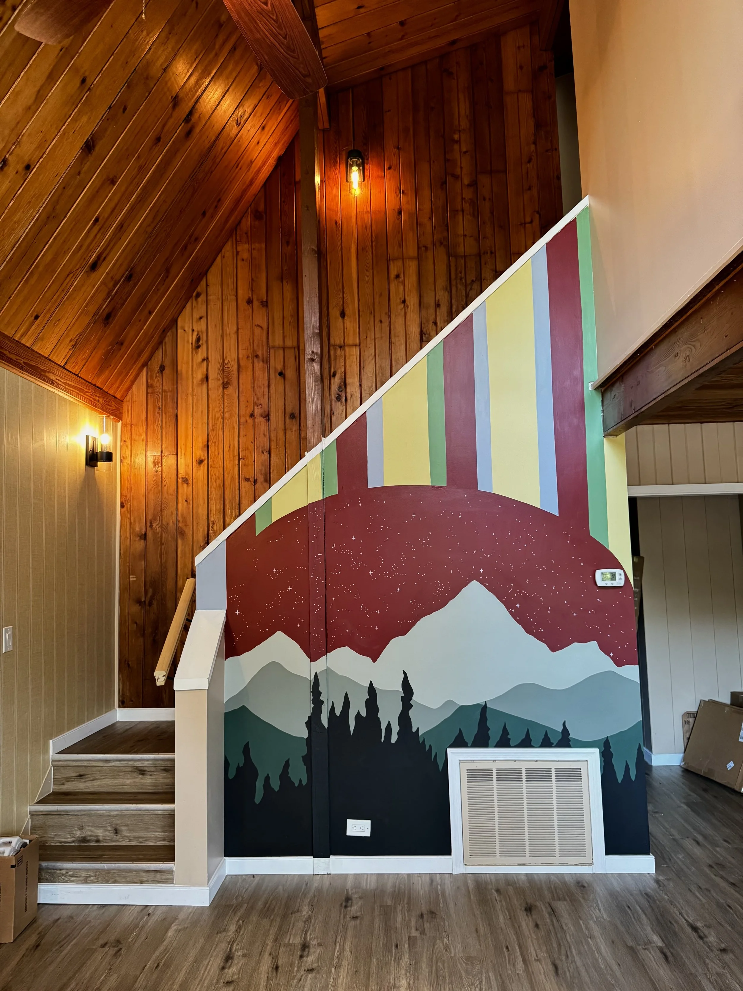 Finished mountain and forest mural beneath a staircase in a Virginia Airbnb