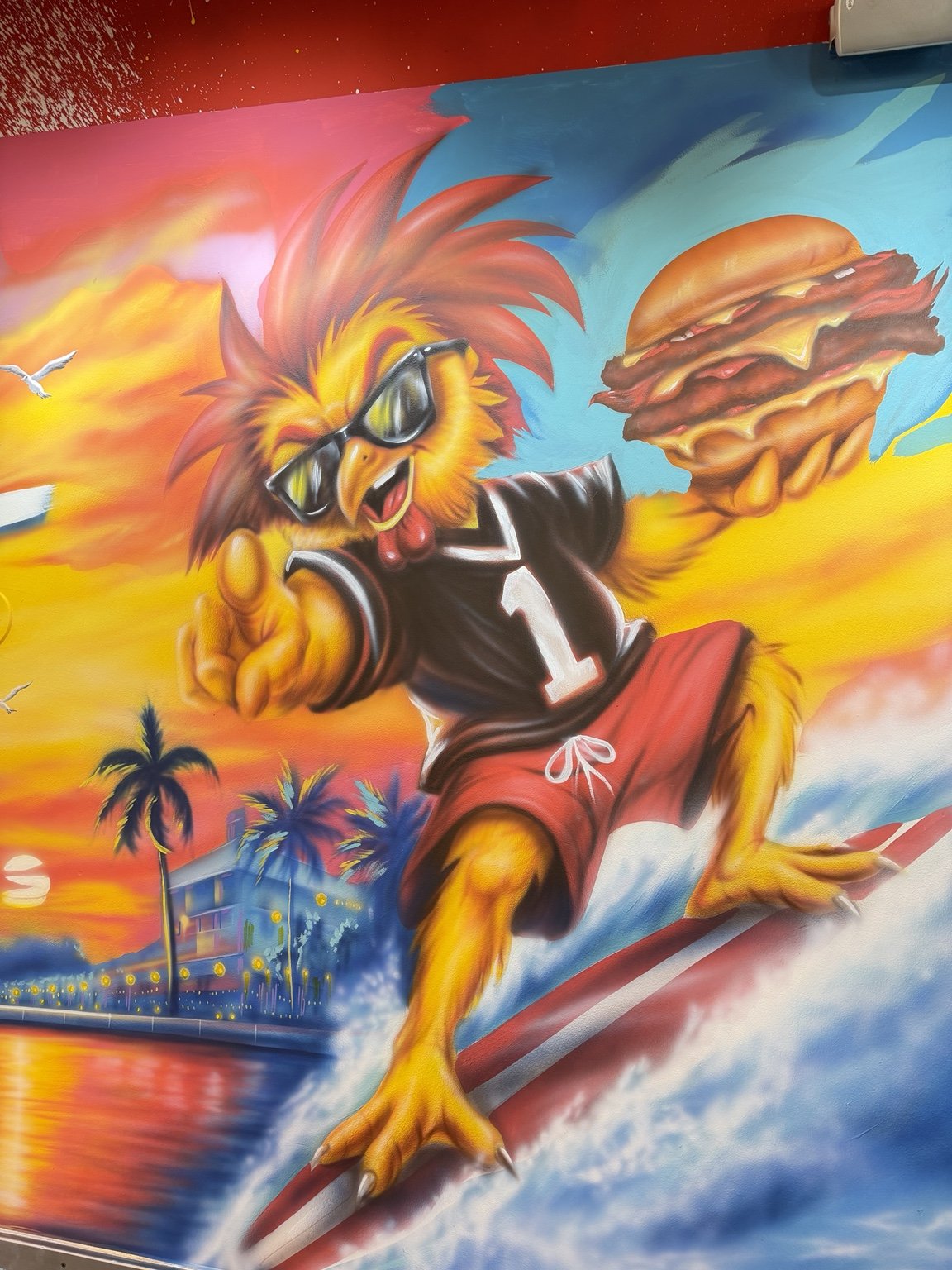 Close-up of the surfing rooster holding a burger in the Boynton Beach restaurant mural