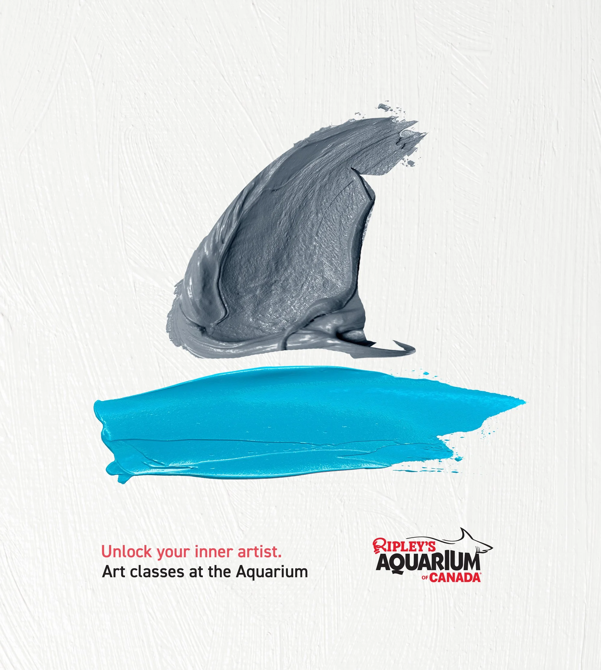An advertisement for art classes at Ripley's Aquarium of Canada featuring a grey paint stroke representing a shark fin and a blue paint stroke representing the water.  the message 'Unlock your inner artist' appears at the bottom.
