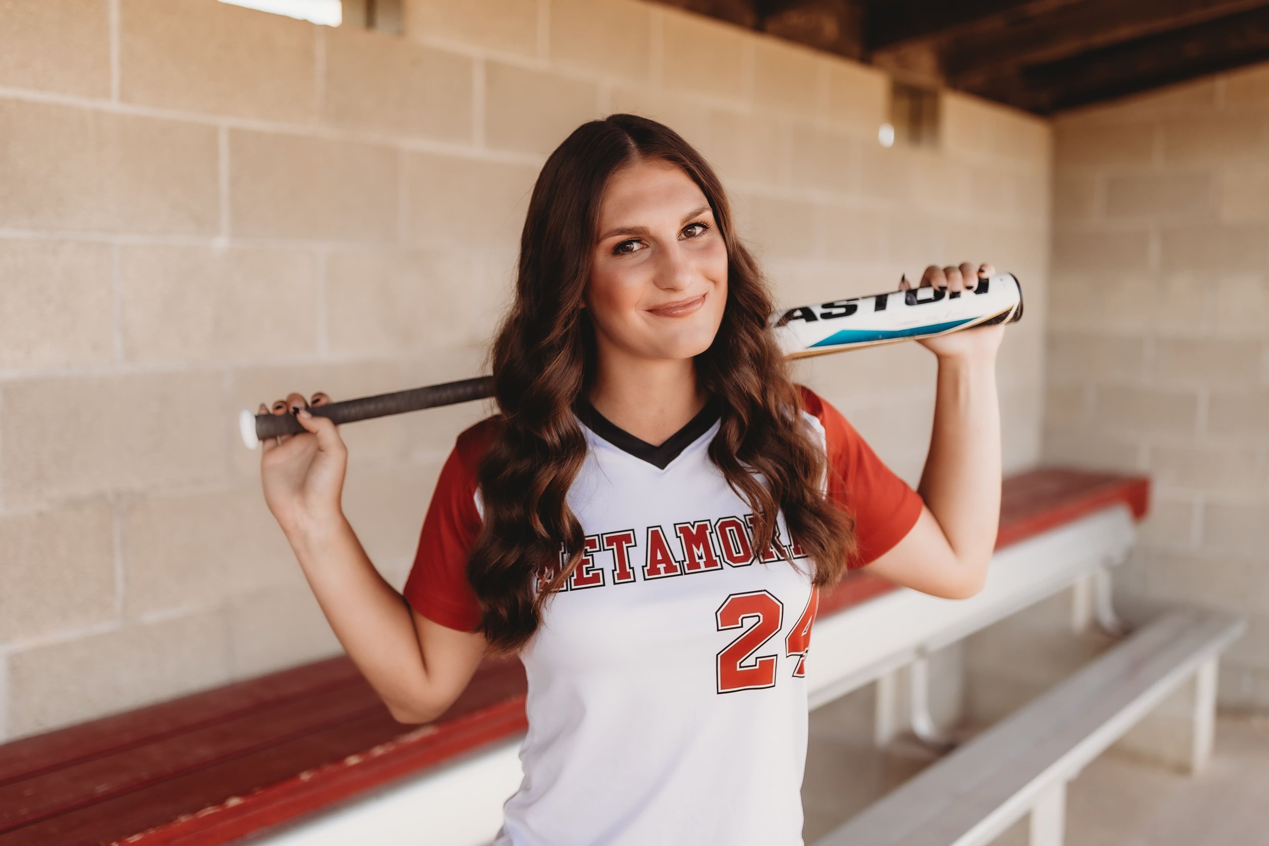  Metamora illinois senior smiles as she wears her softball uniform and over her shoulders is her bat for softball senior picture ideas 