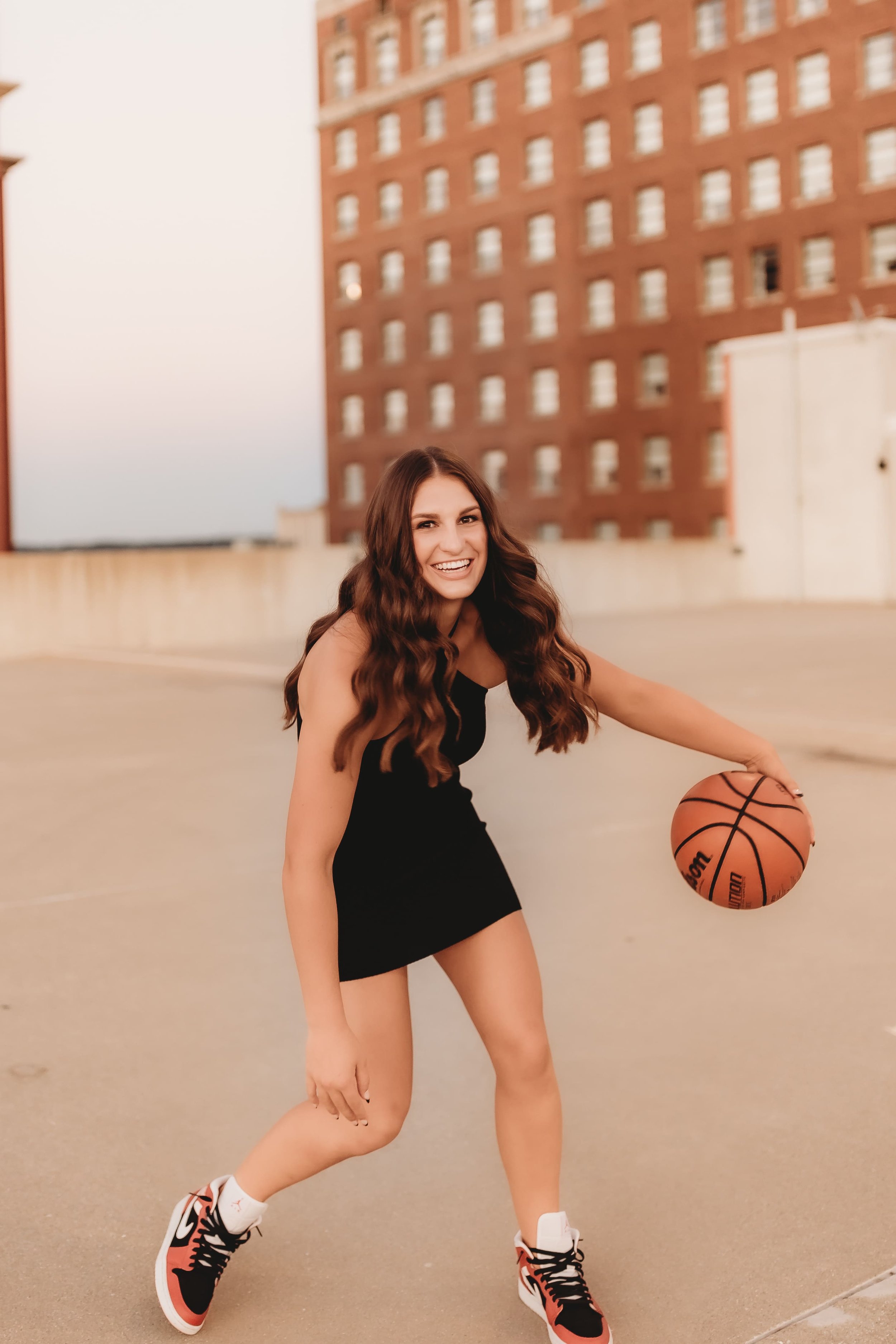  Senior girls basketball player dribbles a basketball on a downtown peoria rooftop while posing for senior pictures basketball 