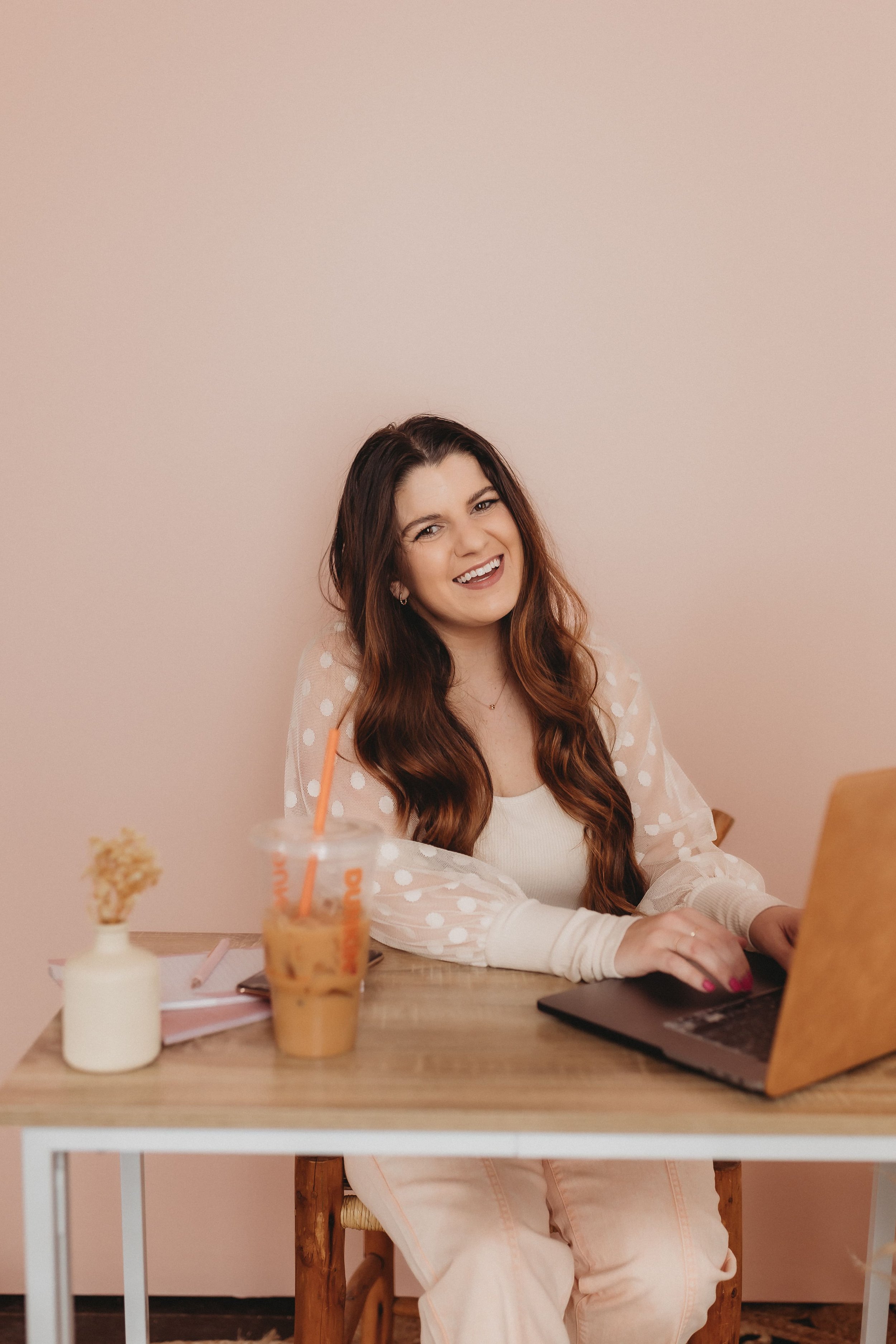  hannah smiles from behind her computer during her brand photos 