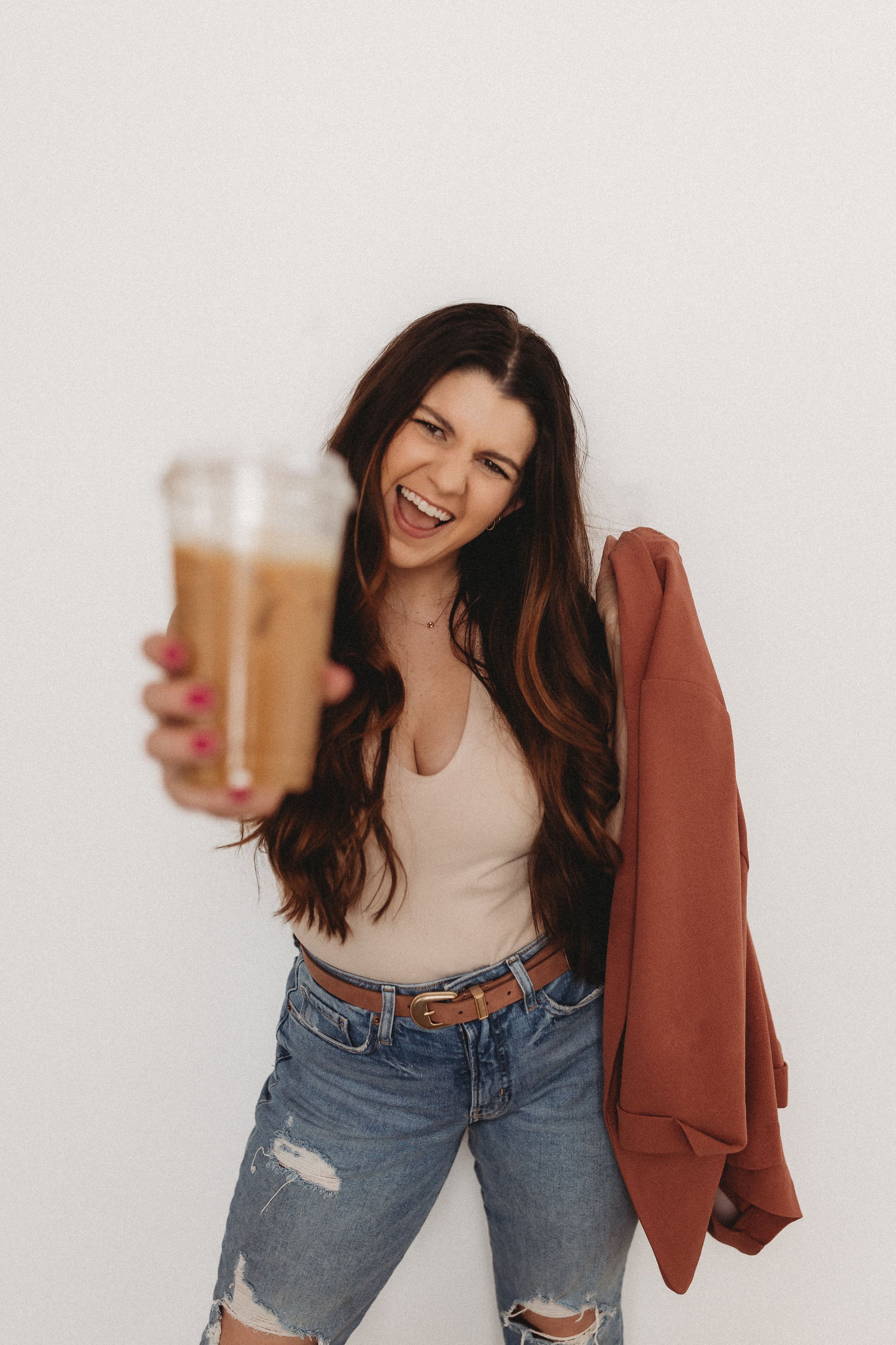  hannah smiles while holding out an iced coffee during her brand photos 